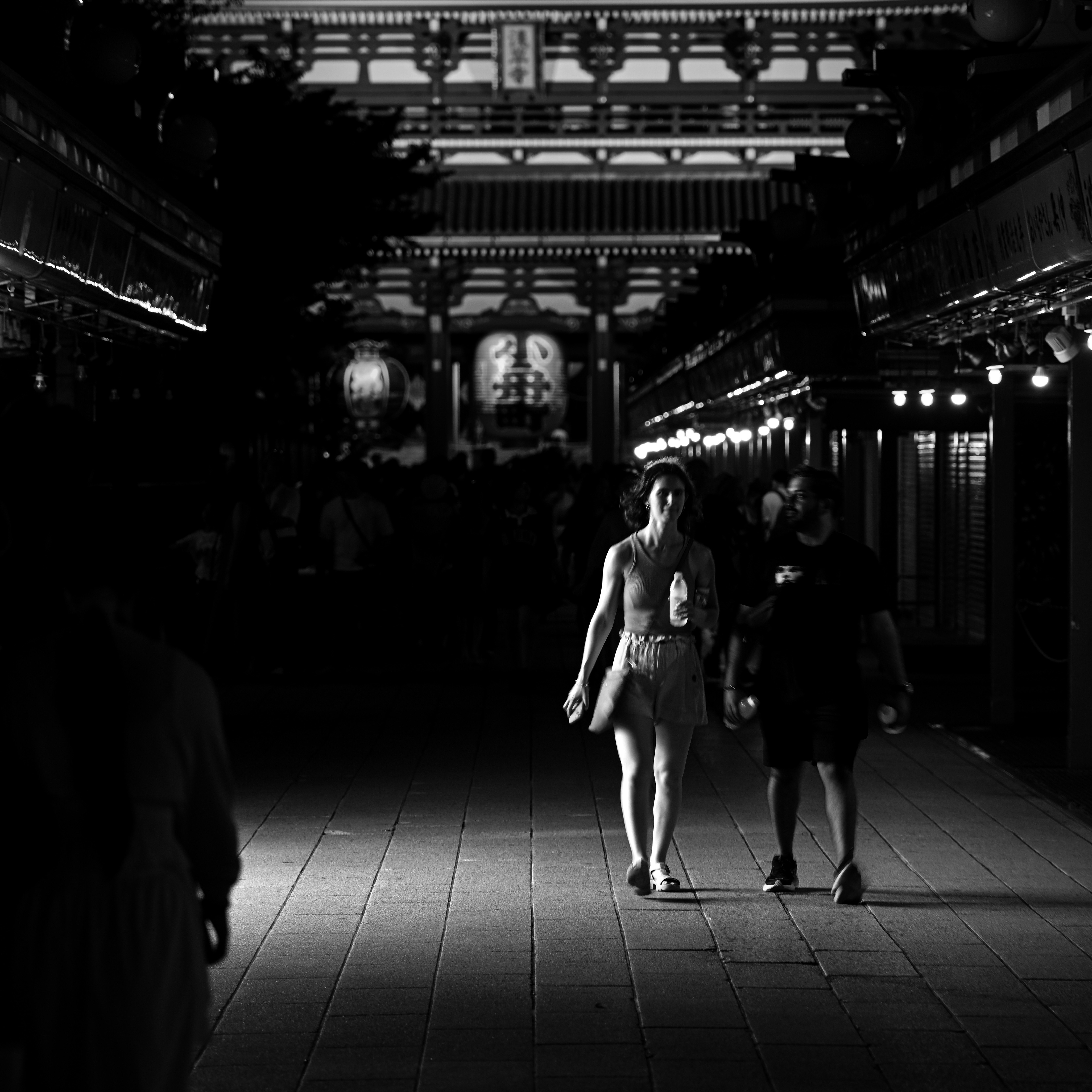 夜の浅草寺仲見世通りを歩くふたりの旅人のモノクロ画像