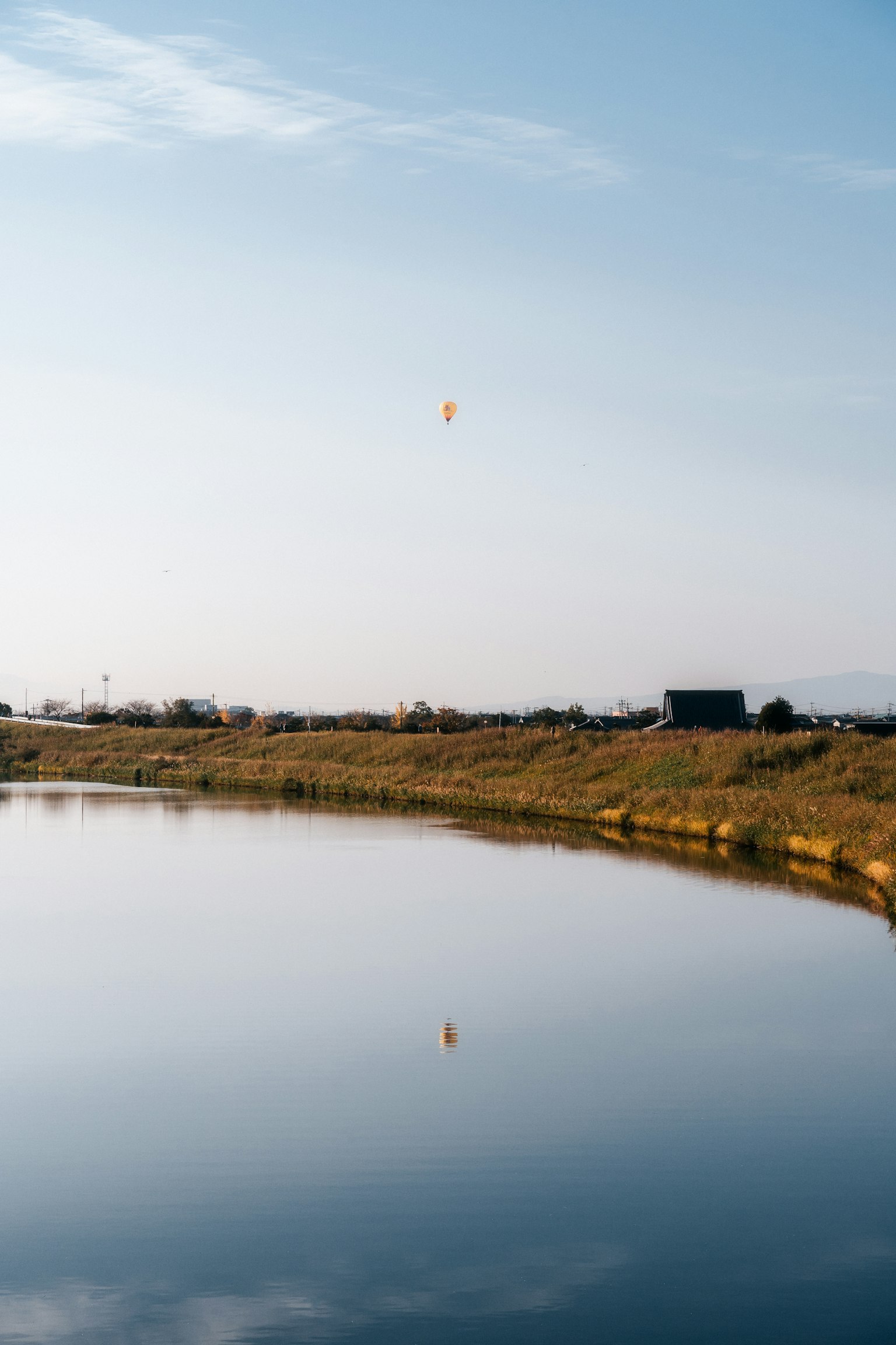 Paesaggio di superficie d'acqua serena con un pallone che fluttua sotto un cielo blu e nuvole riflettenti la bellezza naturale