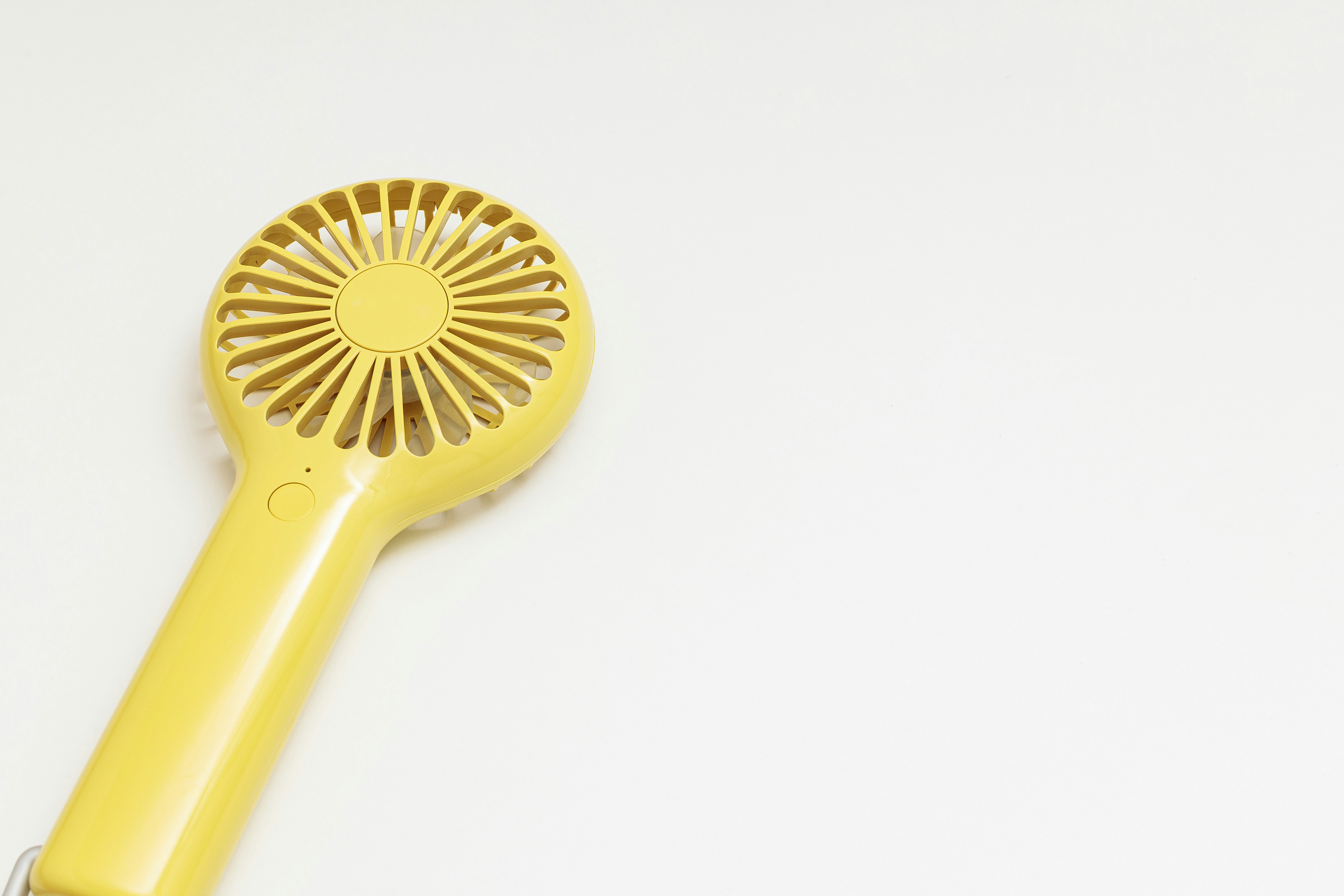 Close-up kipas genggam kuning di latar putih