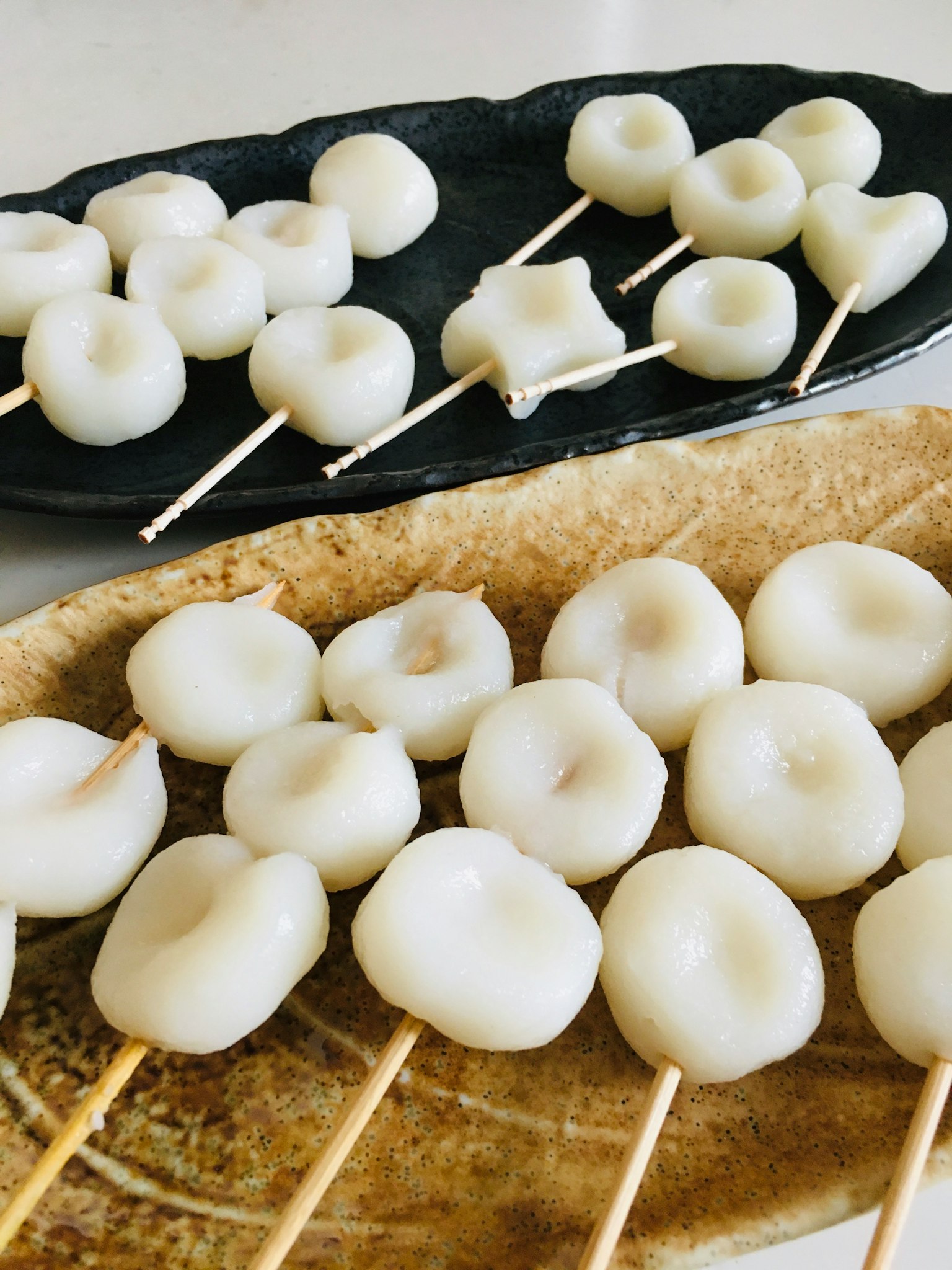 Image of white dumplings on skewers arranged on two plates