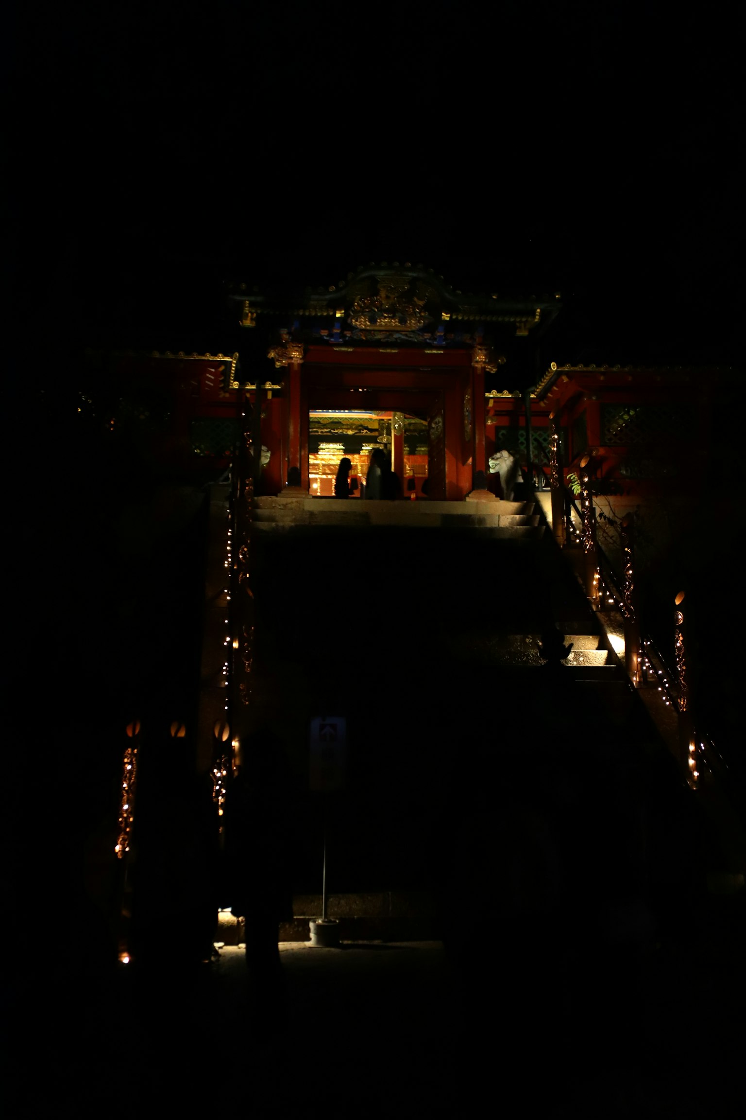 Illuminated entrance of a shrine with stairs at night