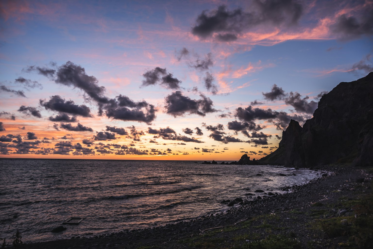 Coastal scene at sunset with clouds and rocky cliffs