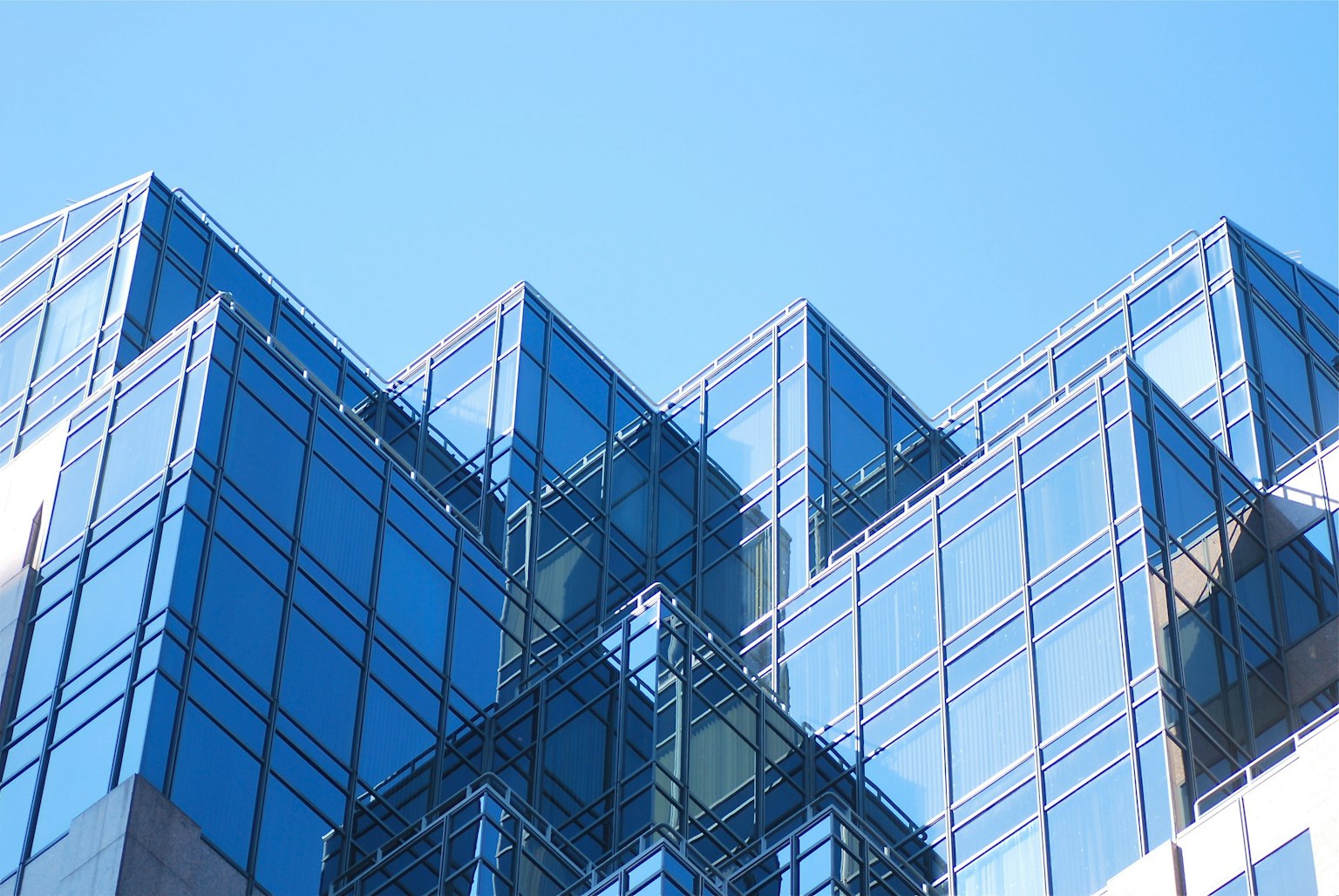 Partie d'un bâtiment moderne en verre sous un ciel bleu