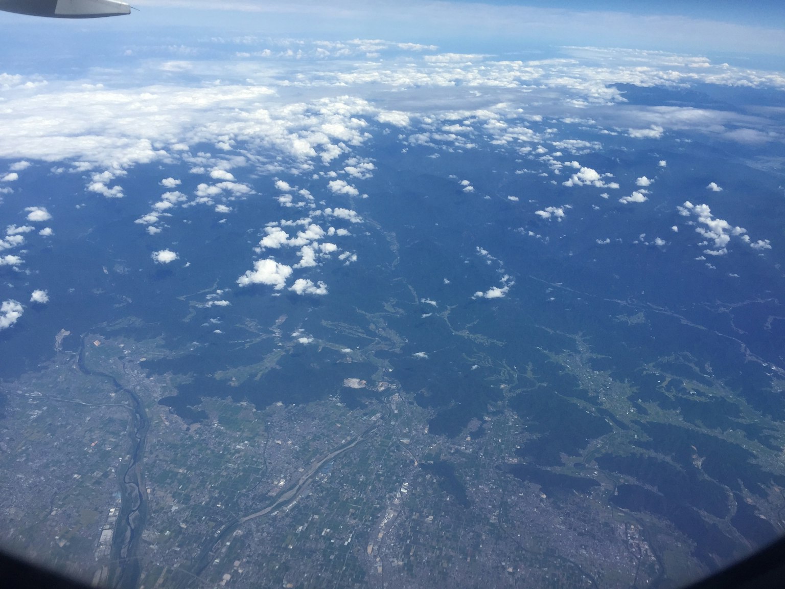 Vista aerea di nuvole e paesaggio verde da un finestrino dell'aereo