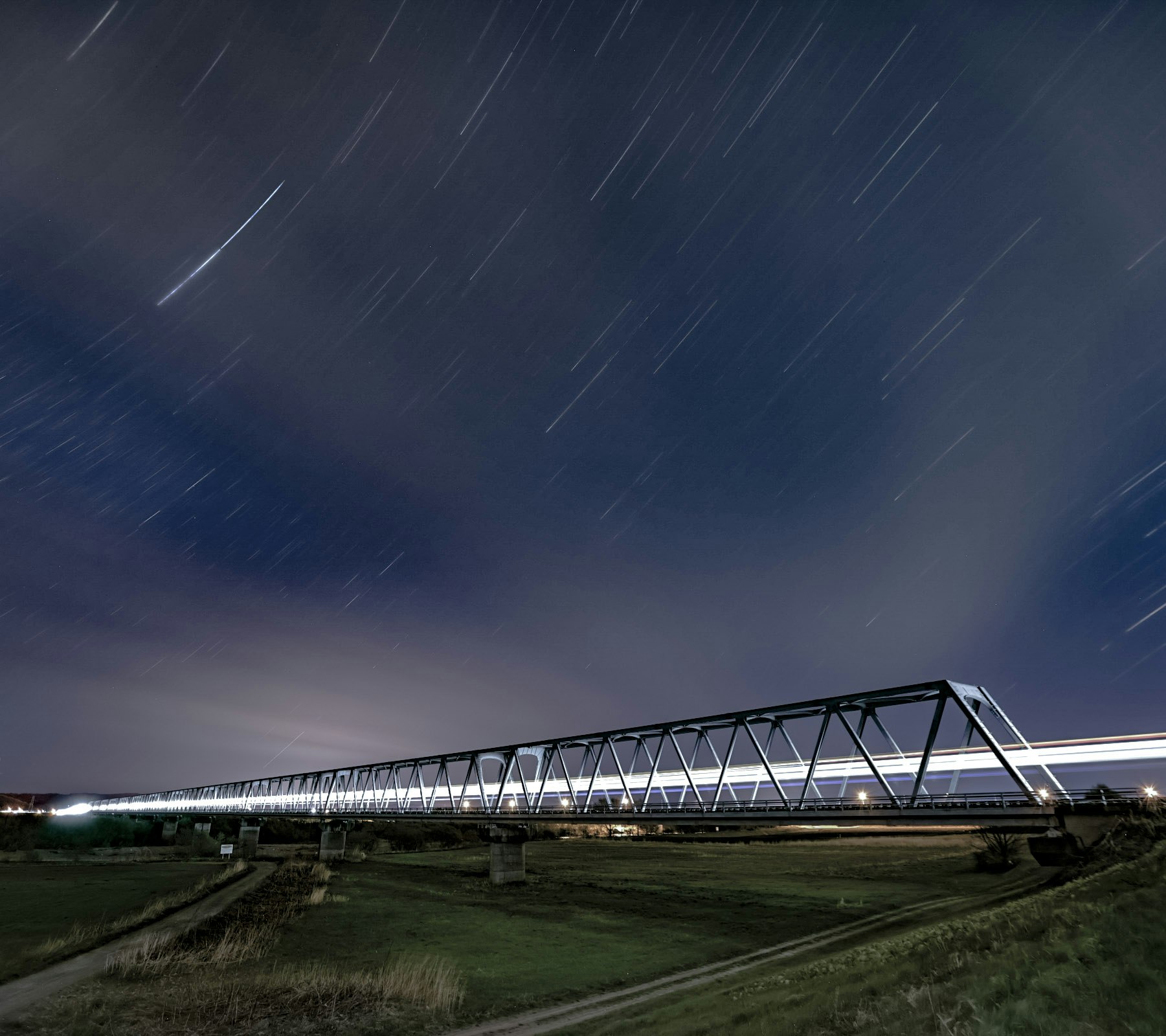 night sky over a long bridge and railway tracks