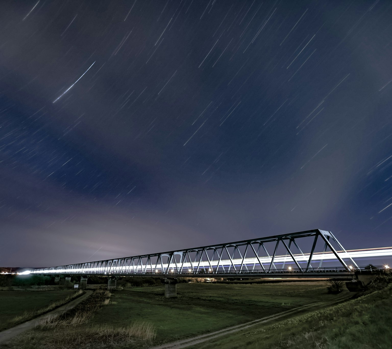 Foto a lunga esposizione di un ponte ferroviario sotto un cielo stellato