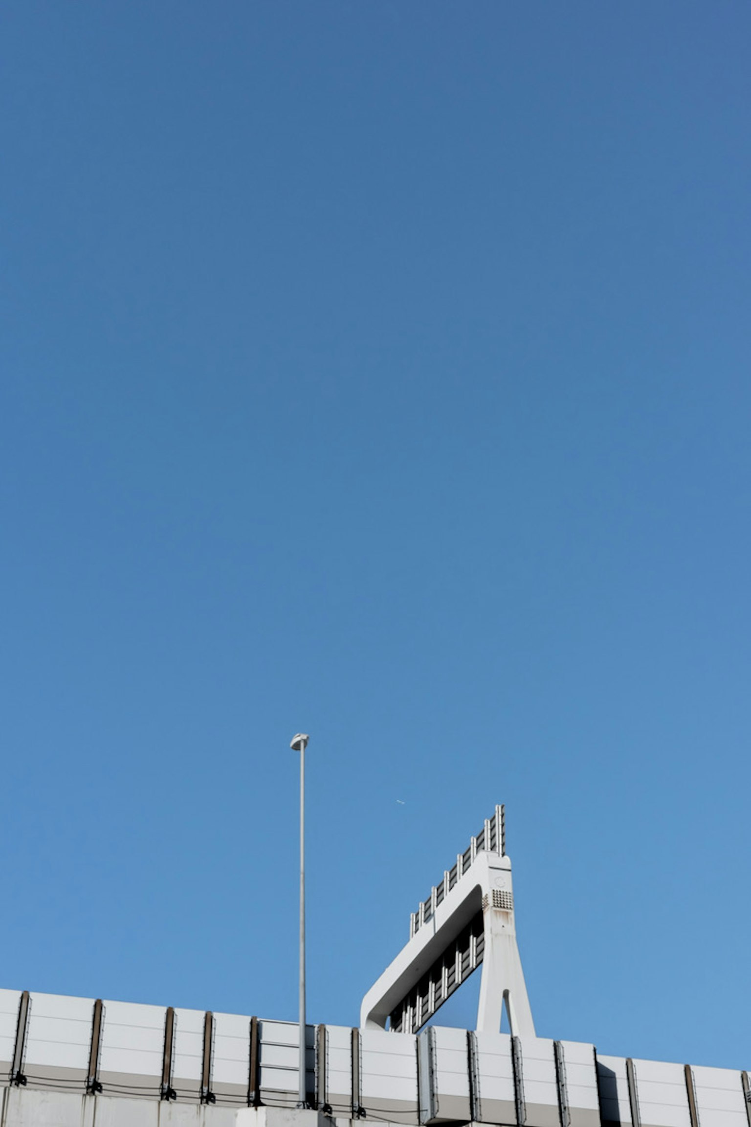 Parte di un edificio moderno con struttura elevata sotto un cielo blu chiaro