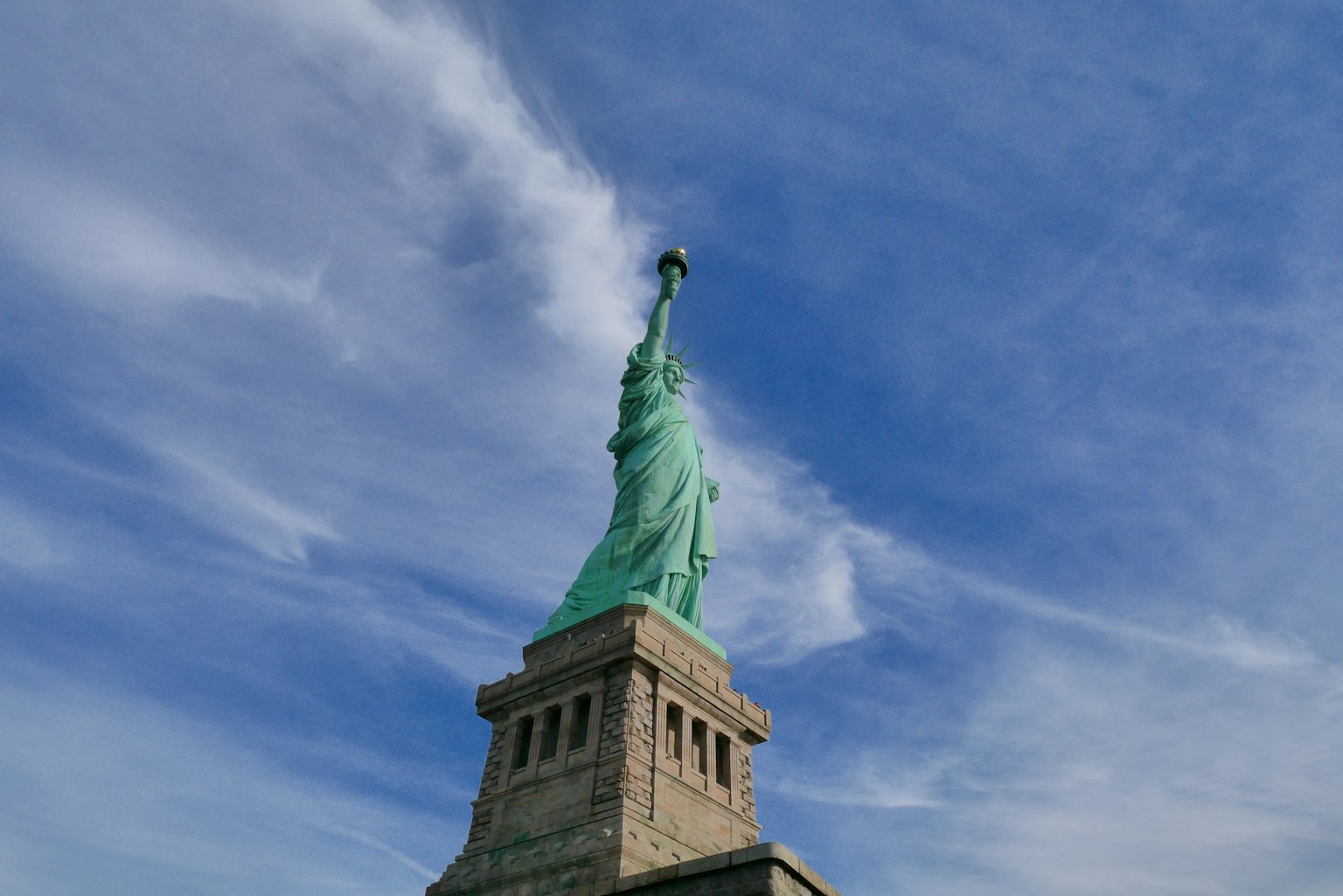 Die Freiheitsstatue steht vor einem blauen Himmel