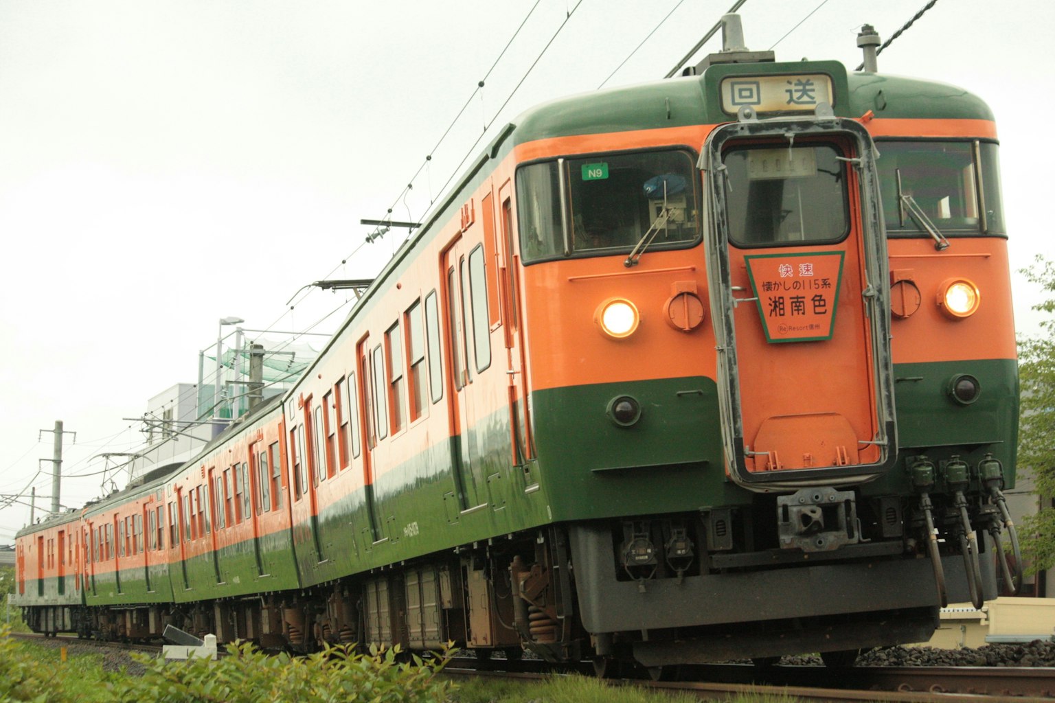 Un treno arancione e verde che corre sui binari