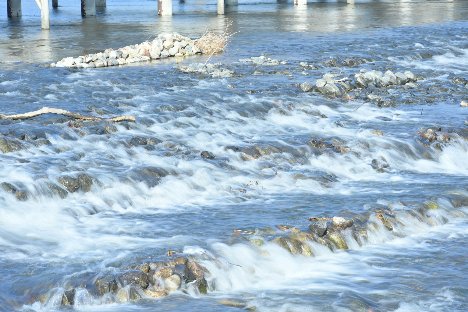 Escena de río fluyendo con pilares de puente visibles