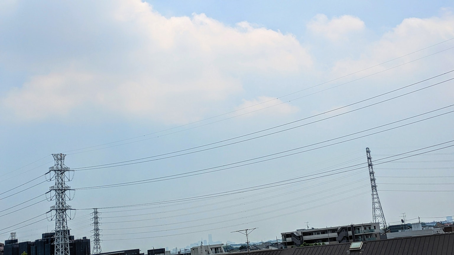 สายไฟและอาคารใต้ท้องฟ้าสีฟ้าพร้อมเมฆสีขาว