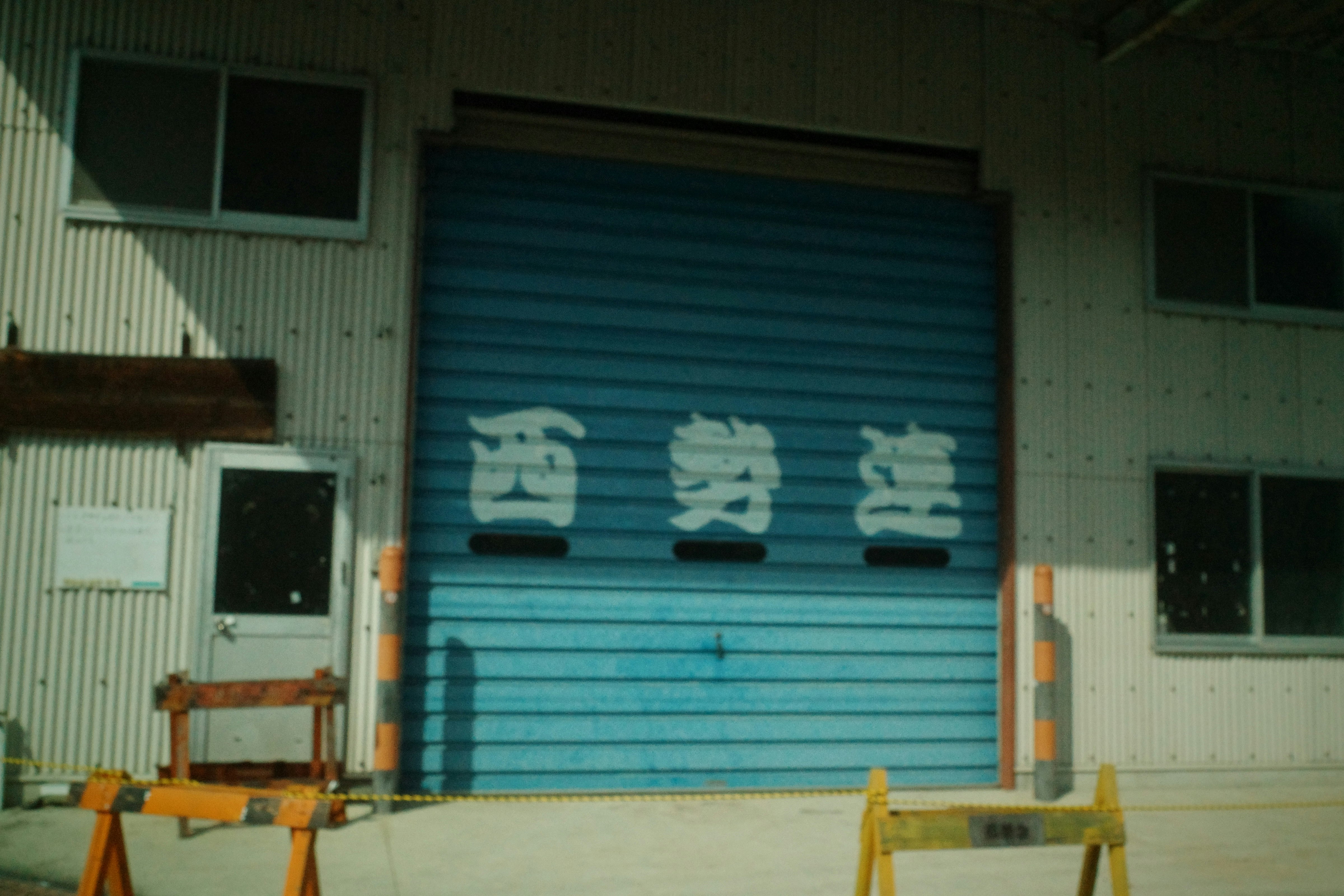 青いドアと白い文字の看板がある工場の外観