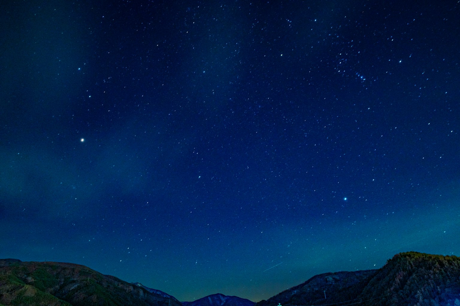 Cielo nocturno lleno de estrellas y paisaje montañoso