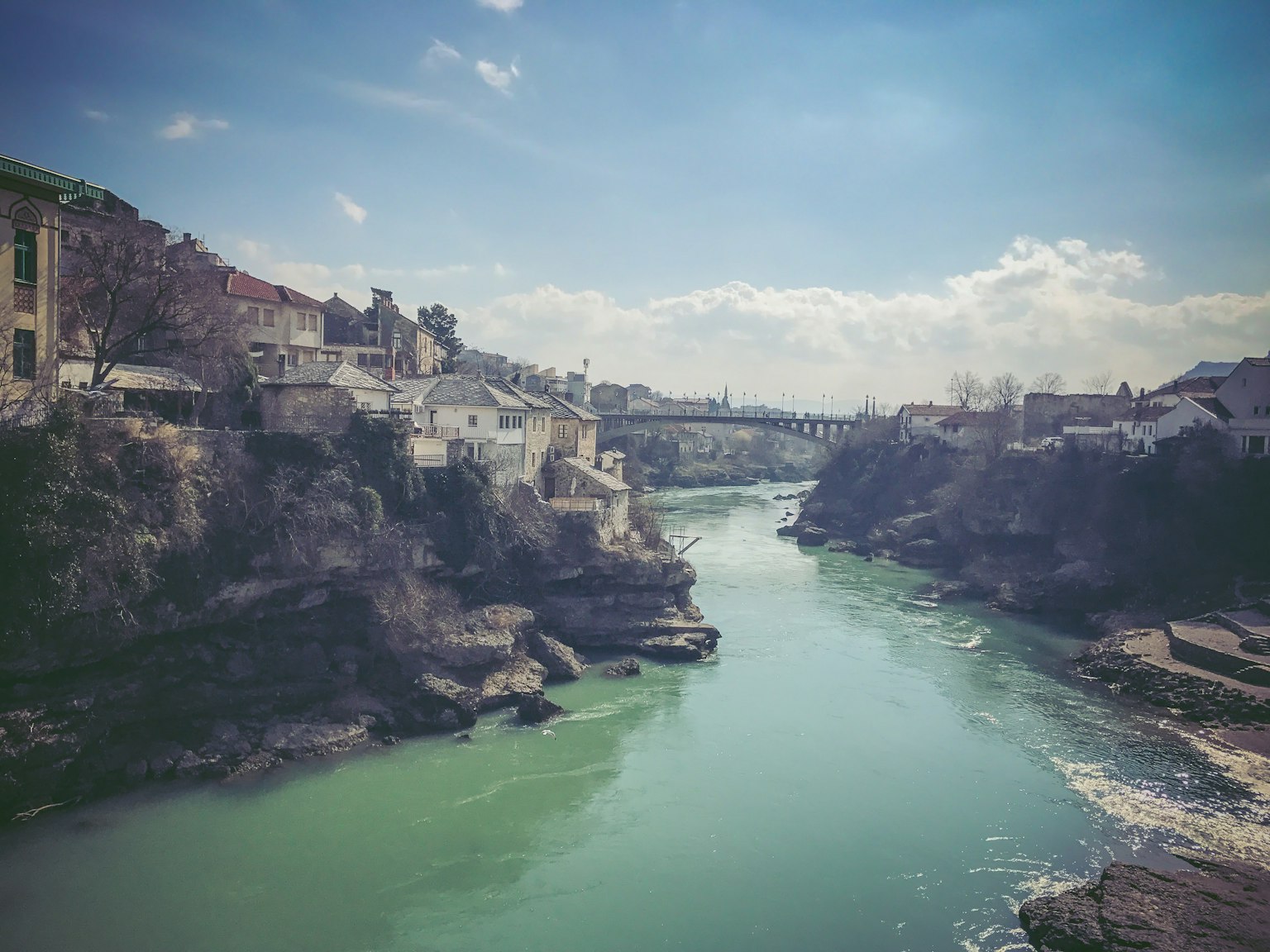 Serene river view with old buildings under a blue sky and clouds
