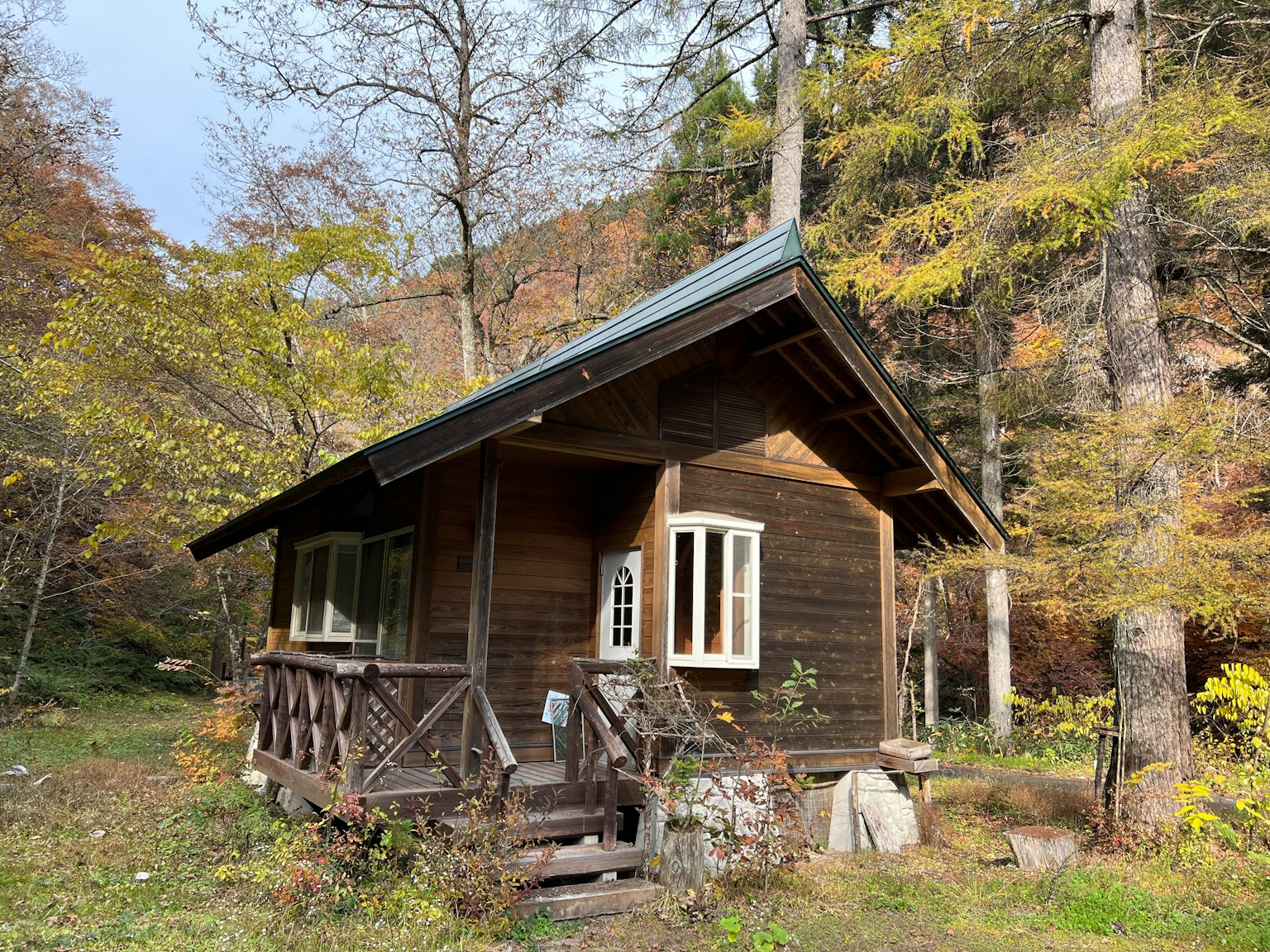 A wooden cabin surrounded by autumn foliage in a forest setting