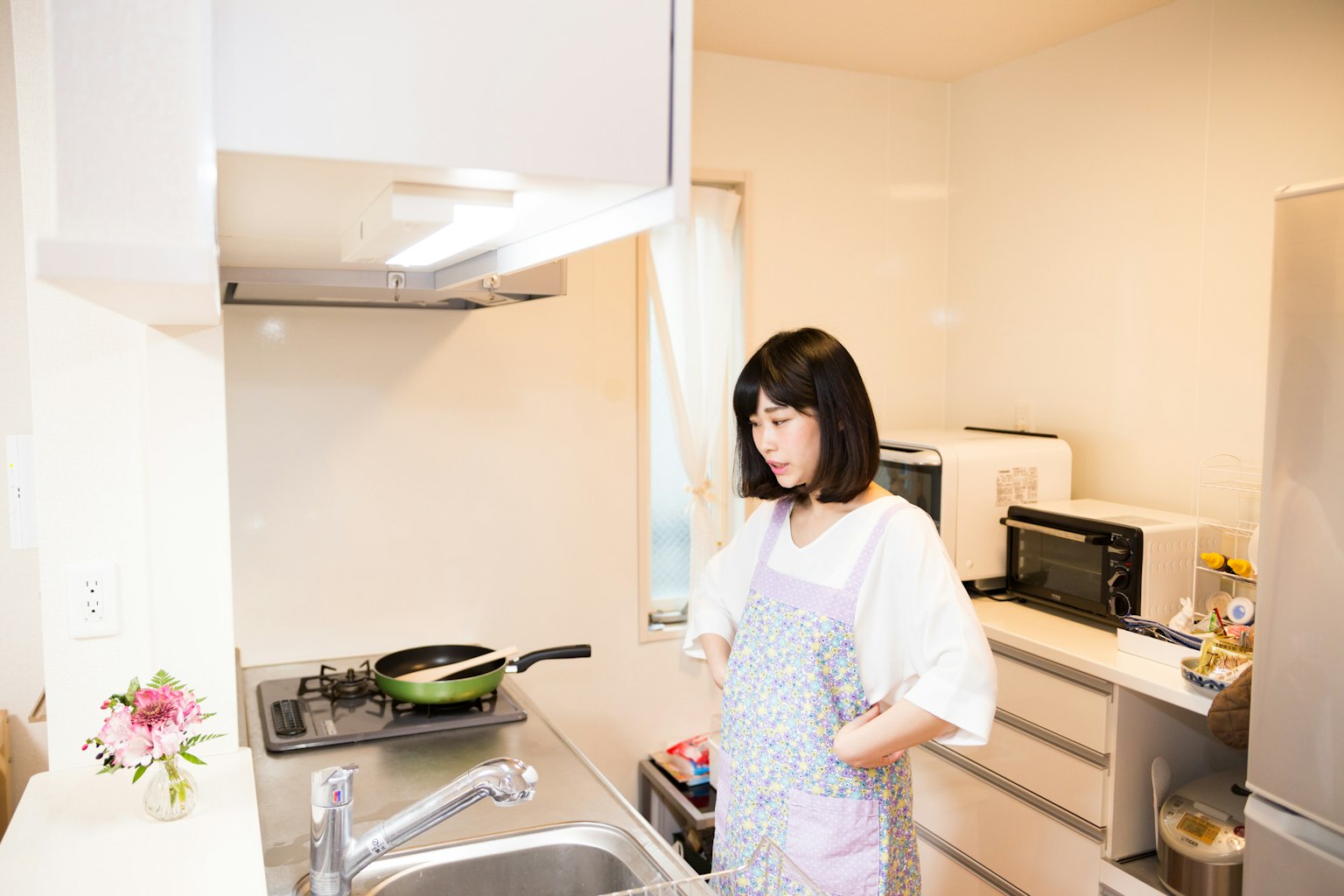 Mujer cocinando en una cocina luminosa con diseño simple y electrodomésticos