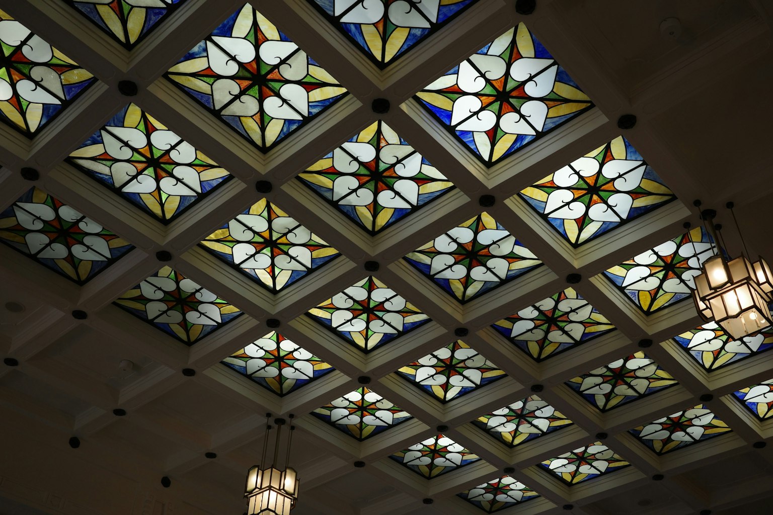 Desain langit-langit kaca patri yang indah dengan pola geometris dan bentuk bunga dari kaca berwarna
