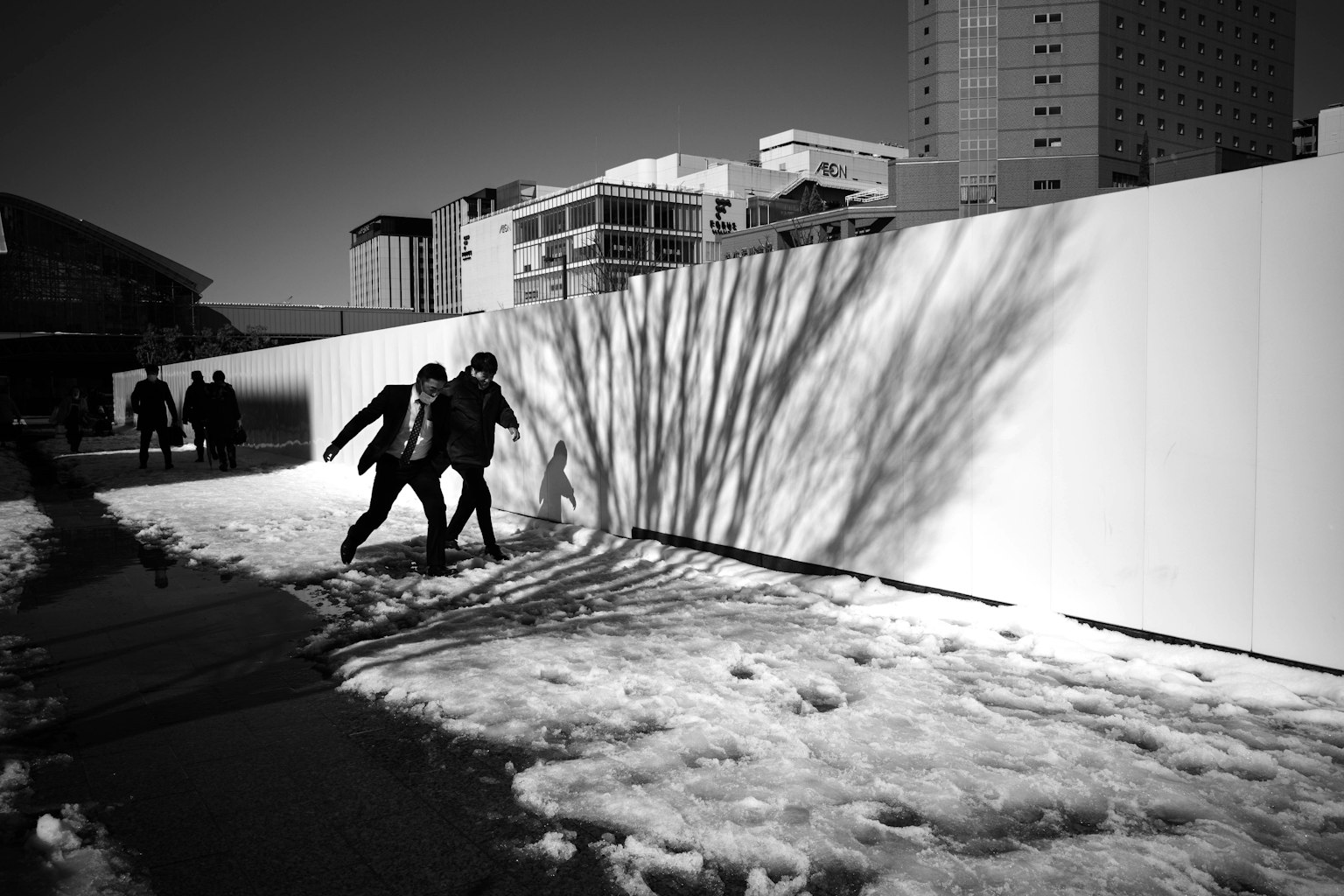 Dos niños jugando en la nieve con sombras de edificios