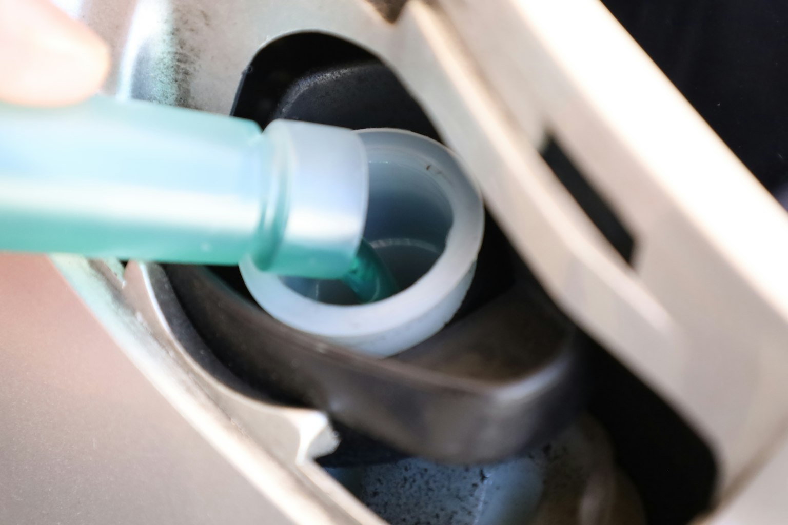 Une personne versant un liquide bleu dans un réservoir de voiture