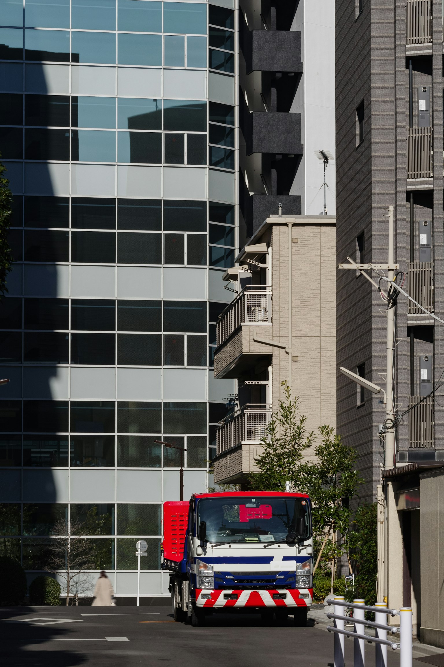 Un camion poubelle bleu et rouge naviguant entre des immeubles élevés