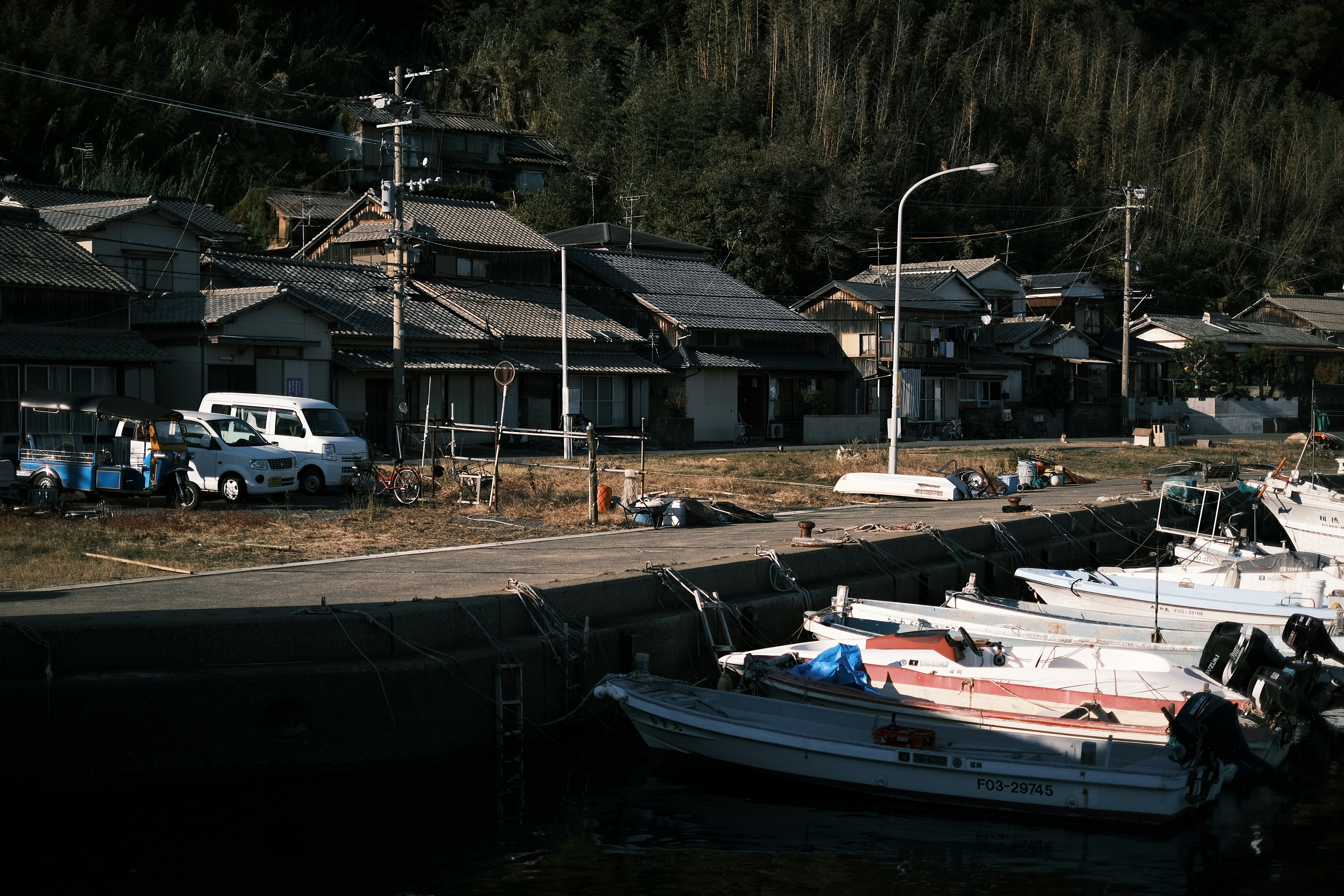 boats moored at a small riverside harbor with houses in the village