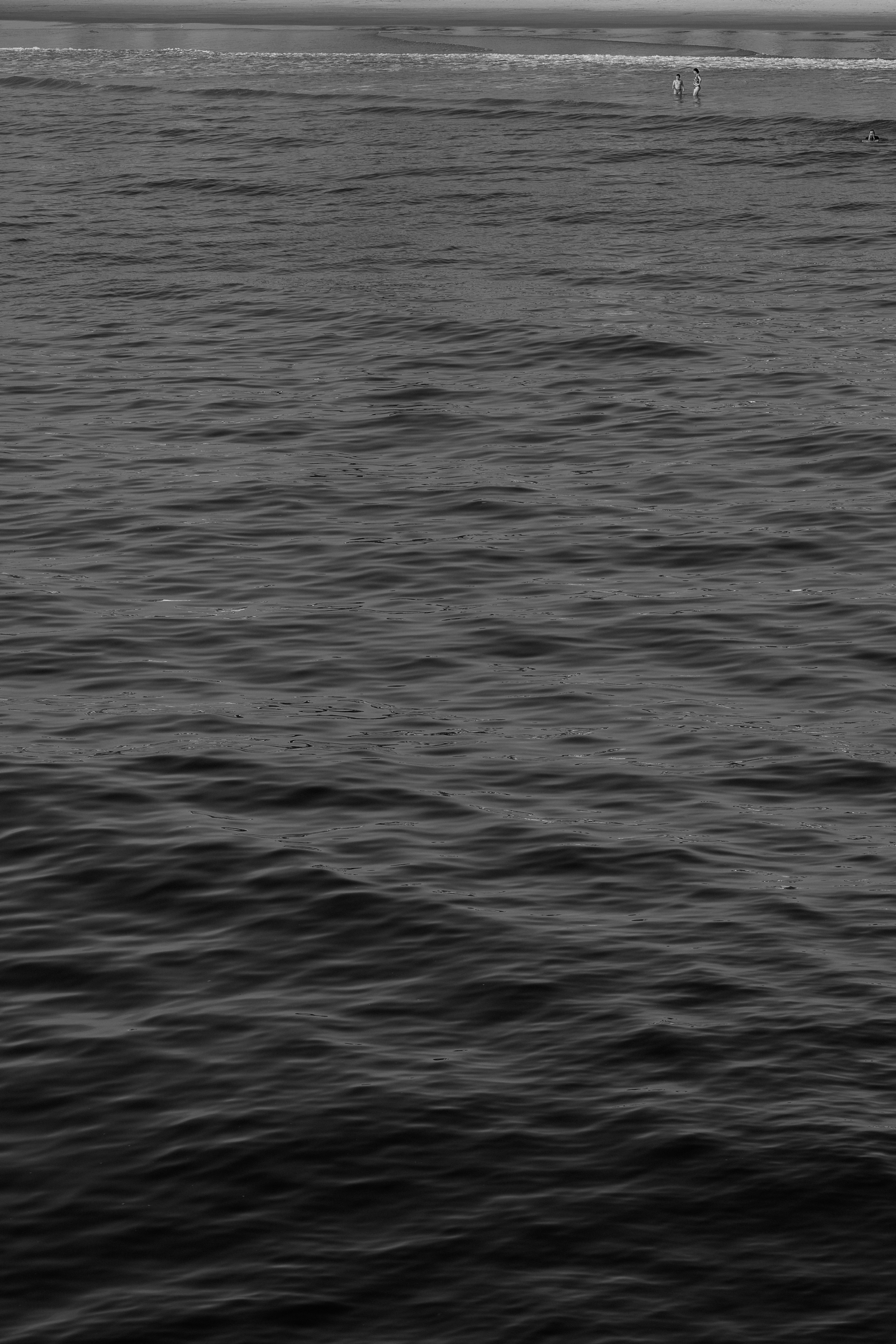 choppy ocean surface with distant small boat silhouettes