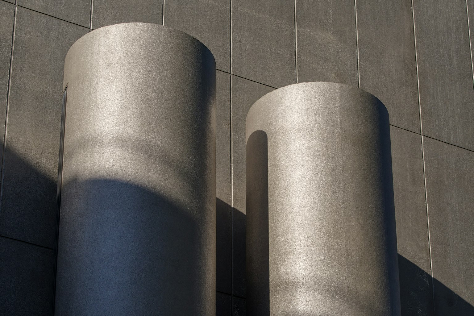 Deux grands cylindres en béton sur l'extérieur d'un bâtiment moderne
