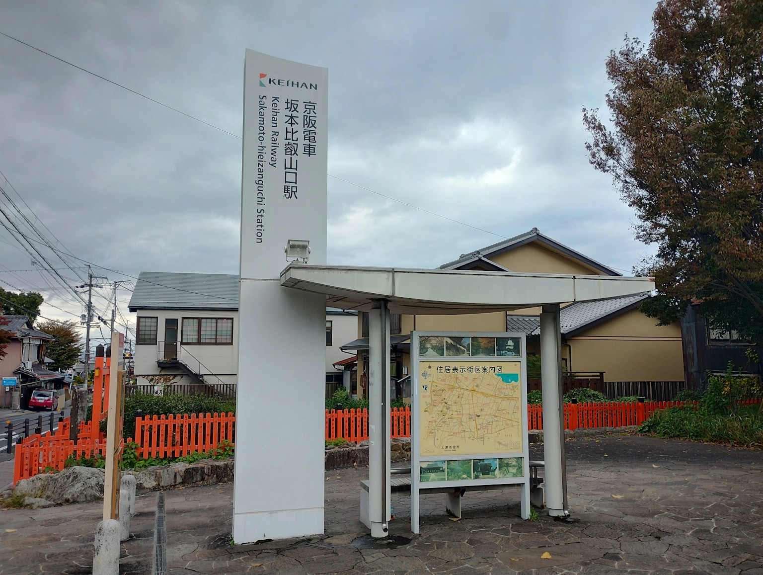 This image shows a white sign under a gray sky with surrounding scenery