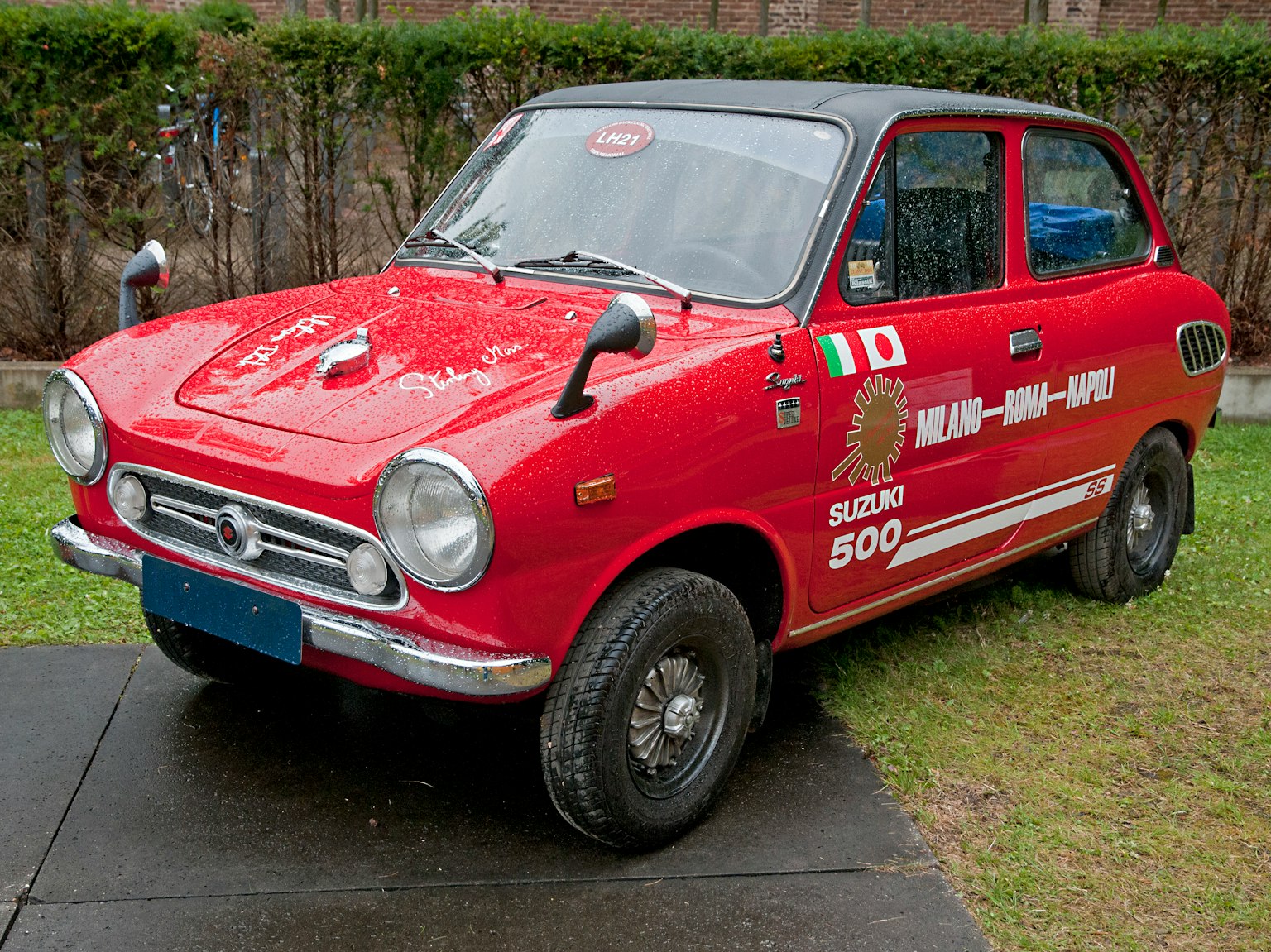 Un coche clásico Fiat 500 rojo aparcado en el césped