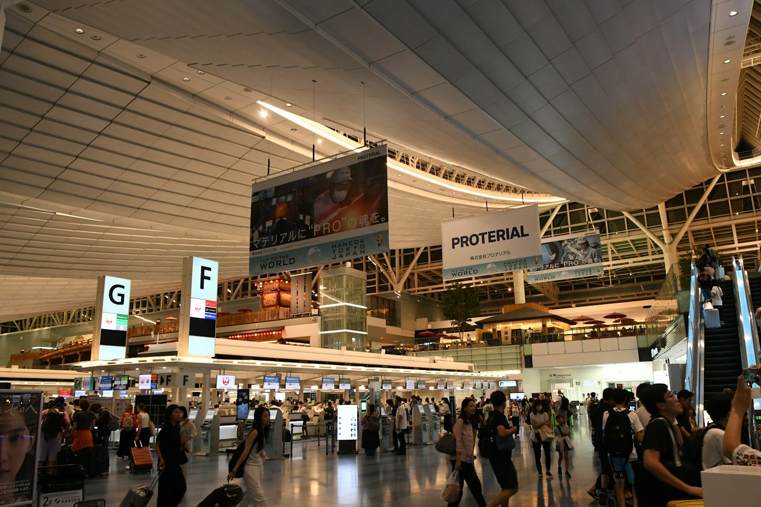 Intérieur spacieux d'un aéroport avec de nombreuses personnes et de grandes bannières publicitaires