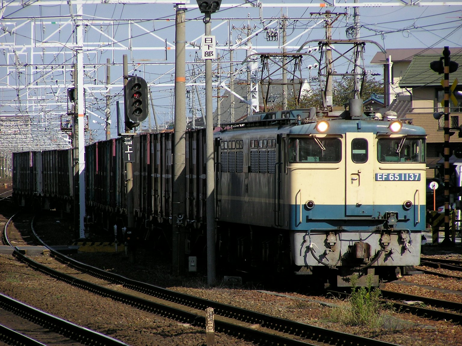 Freight train approaching a station with a blue and white locomotive