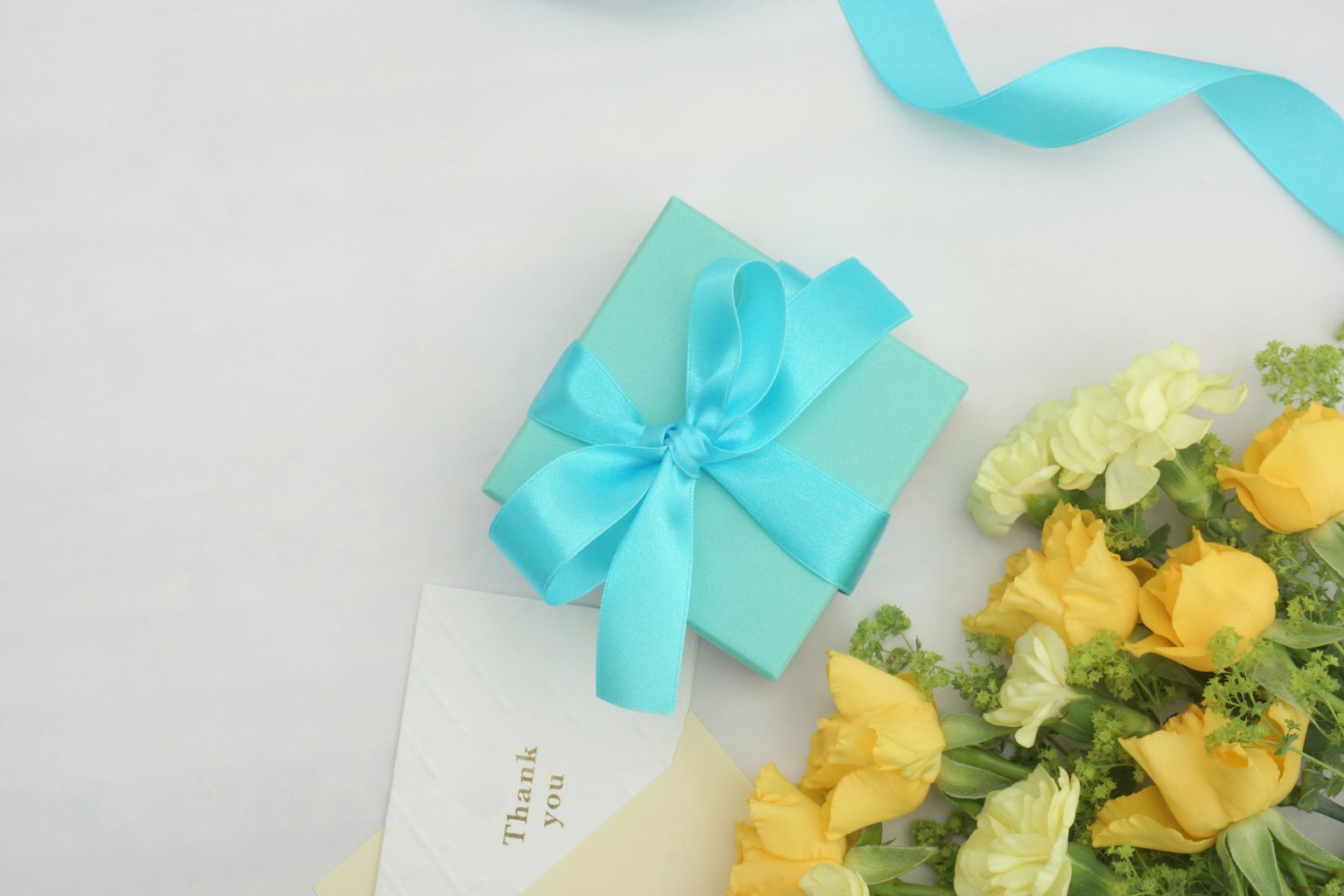 Piccola scatola regalo con un nastro blu e fiori gialli nelle vicinanze