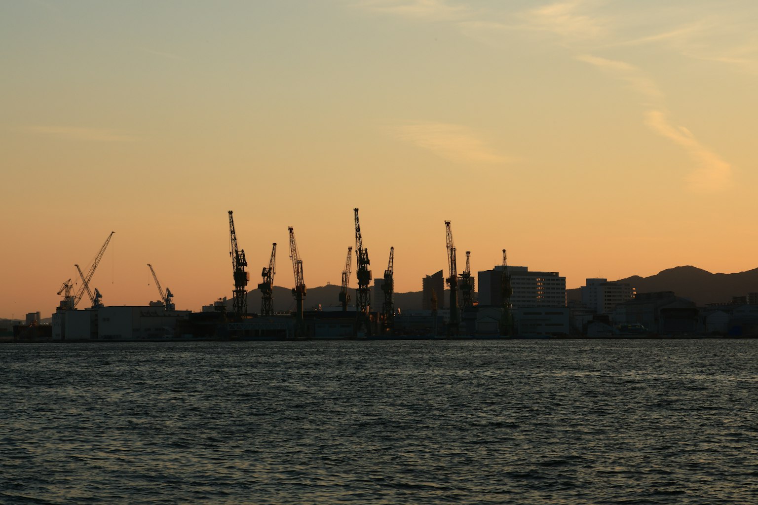 Silhouette di un'area industriale e gru al tramonto