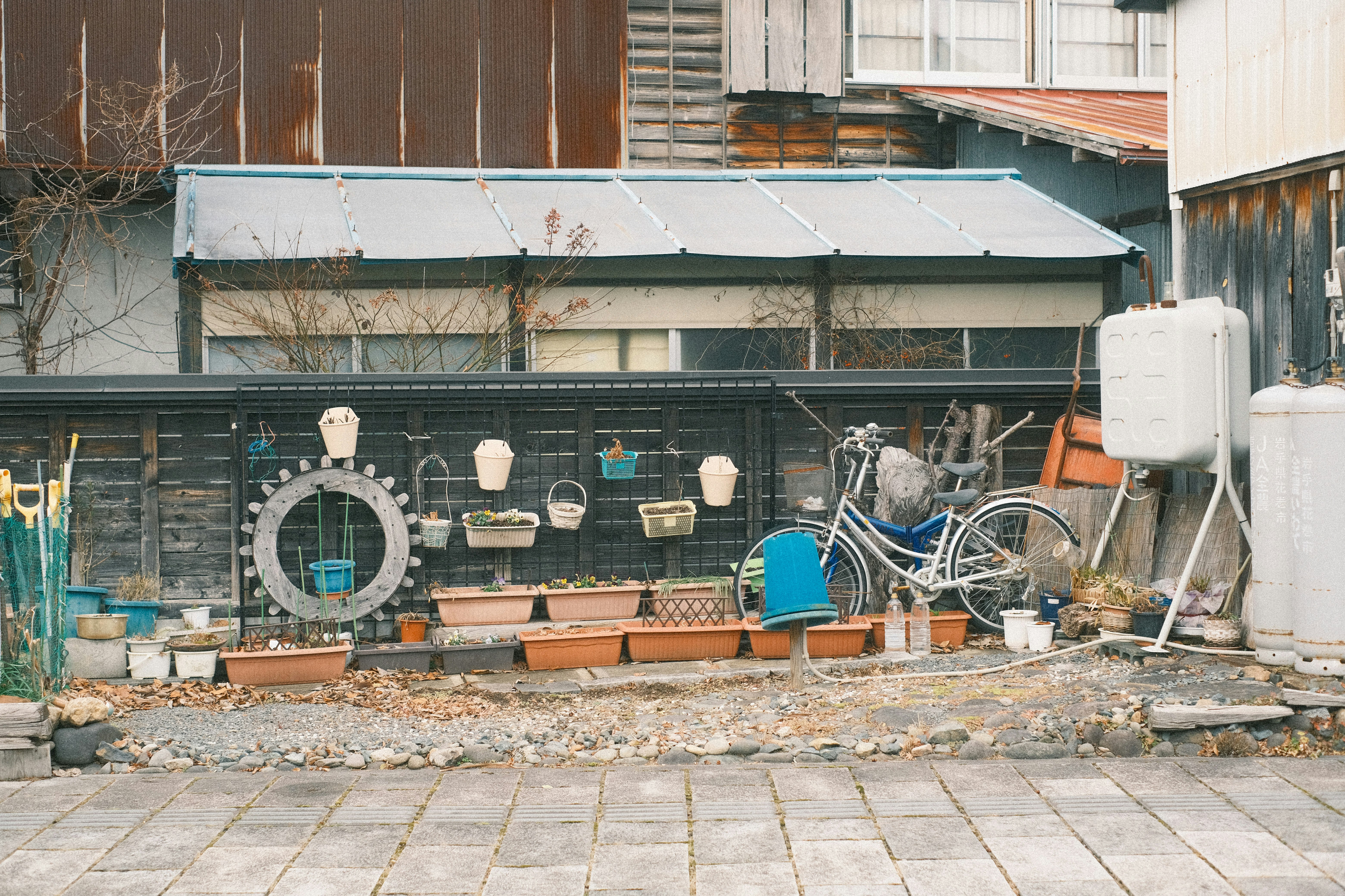 路地裏の自転車と植木鉢が並ぶ小さな物置スペース