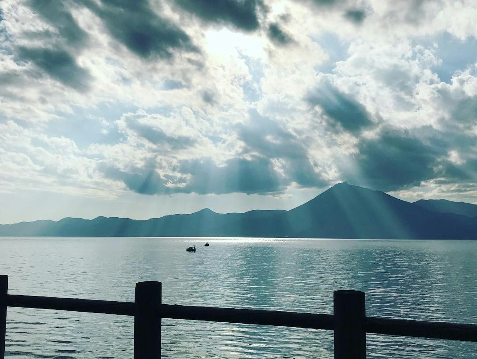 Lac serein avec des montagnes en arrière-plan et de beaux rayons de lumière