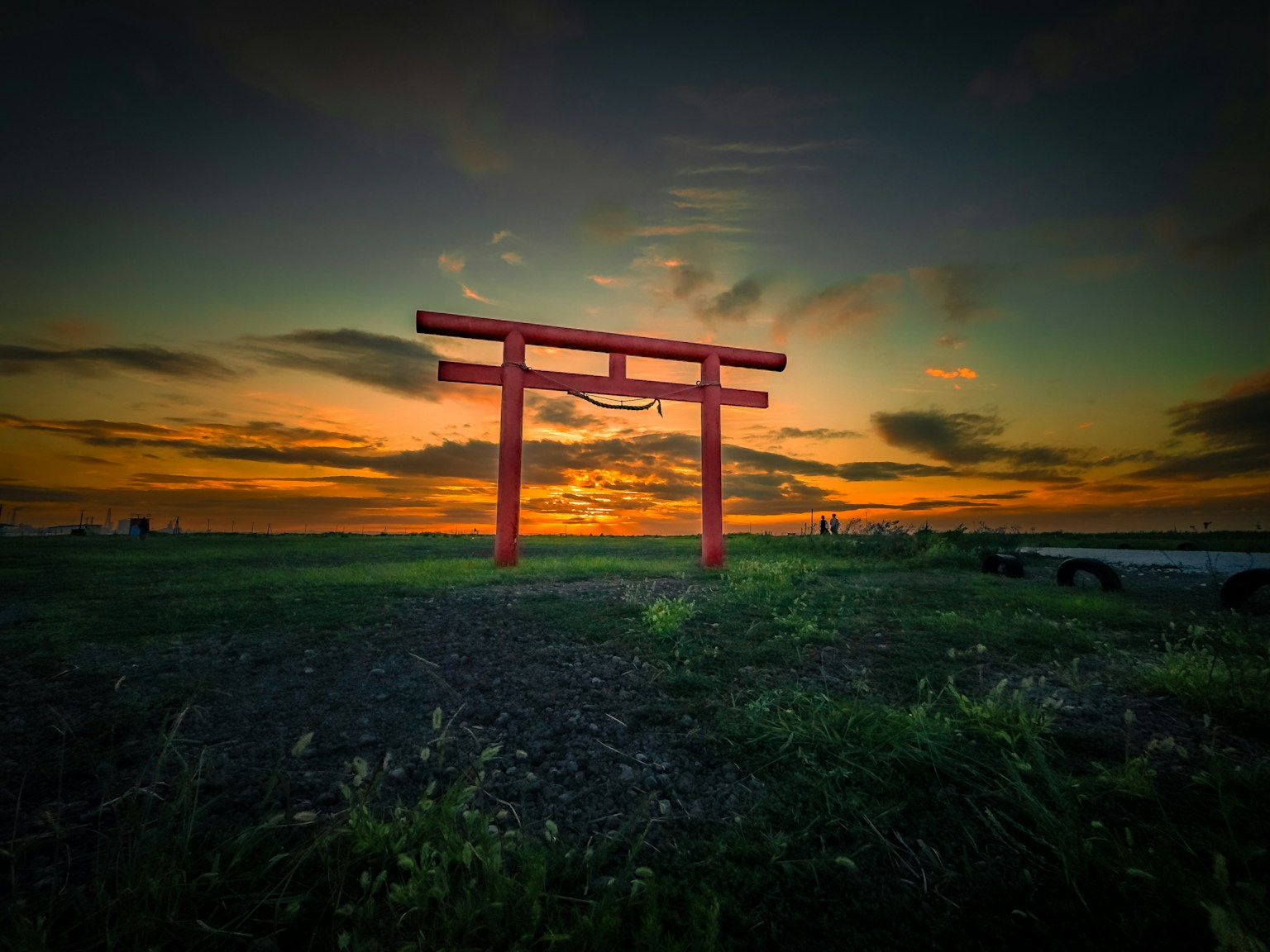 A red torii gate silhouetted against a sunset sky