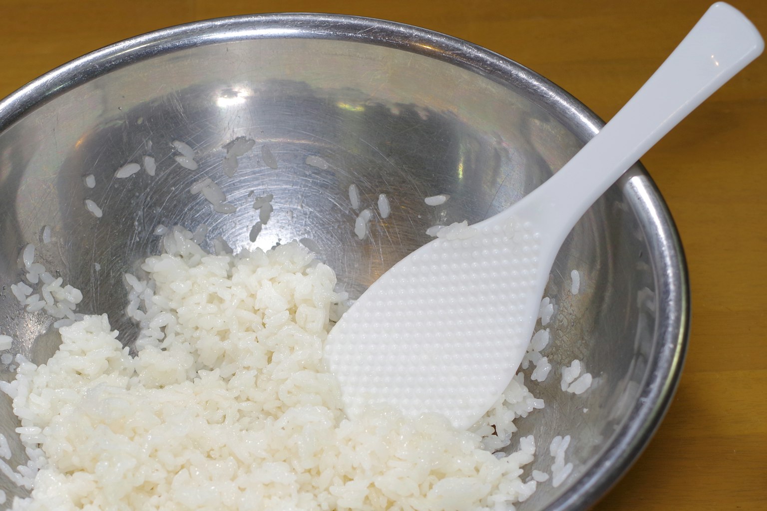 银色碗中的松软米饭和白色铲子