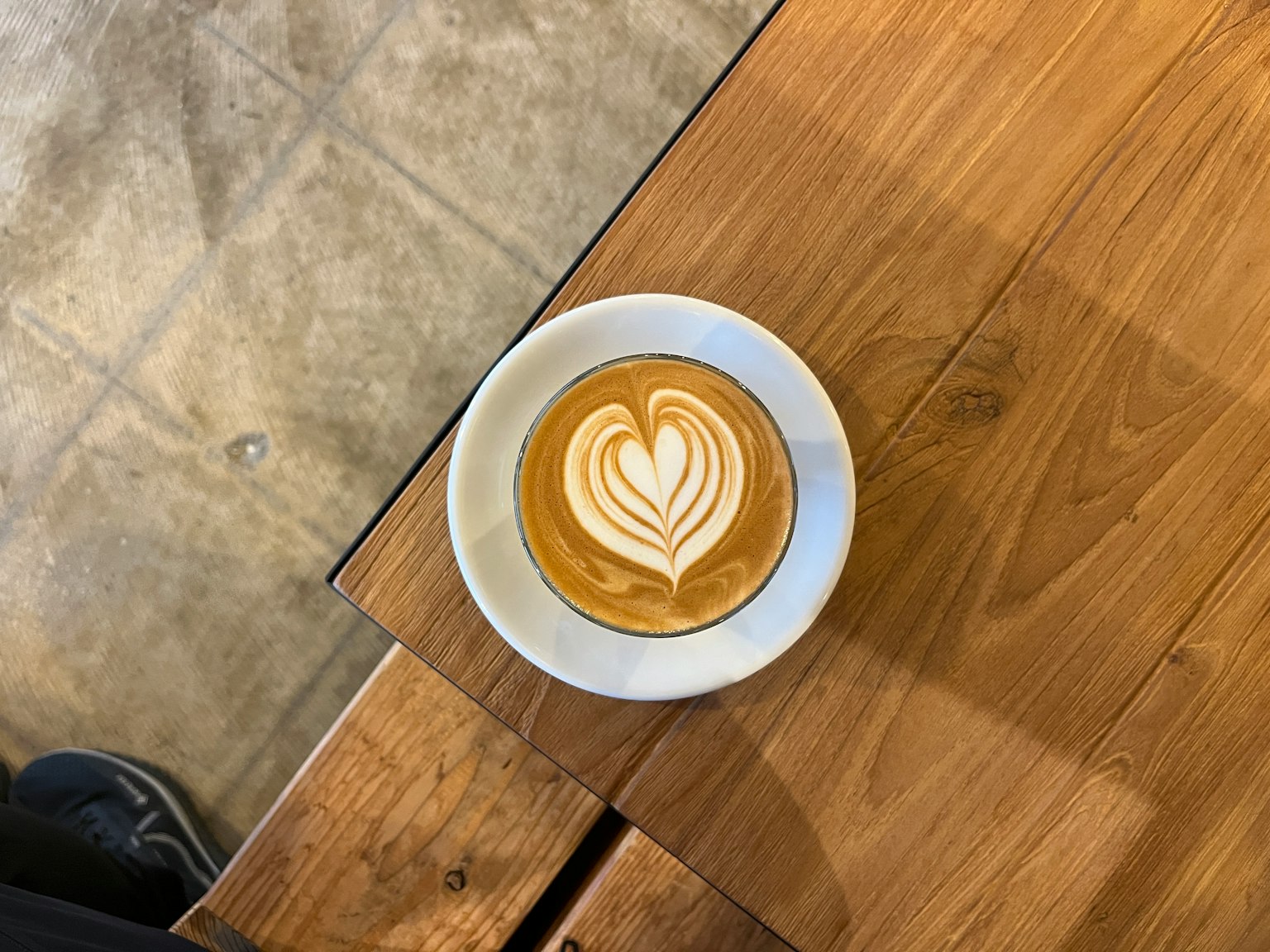 Café avec une art latte en forme de cœur sur une table en bois