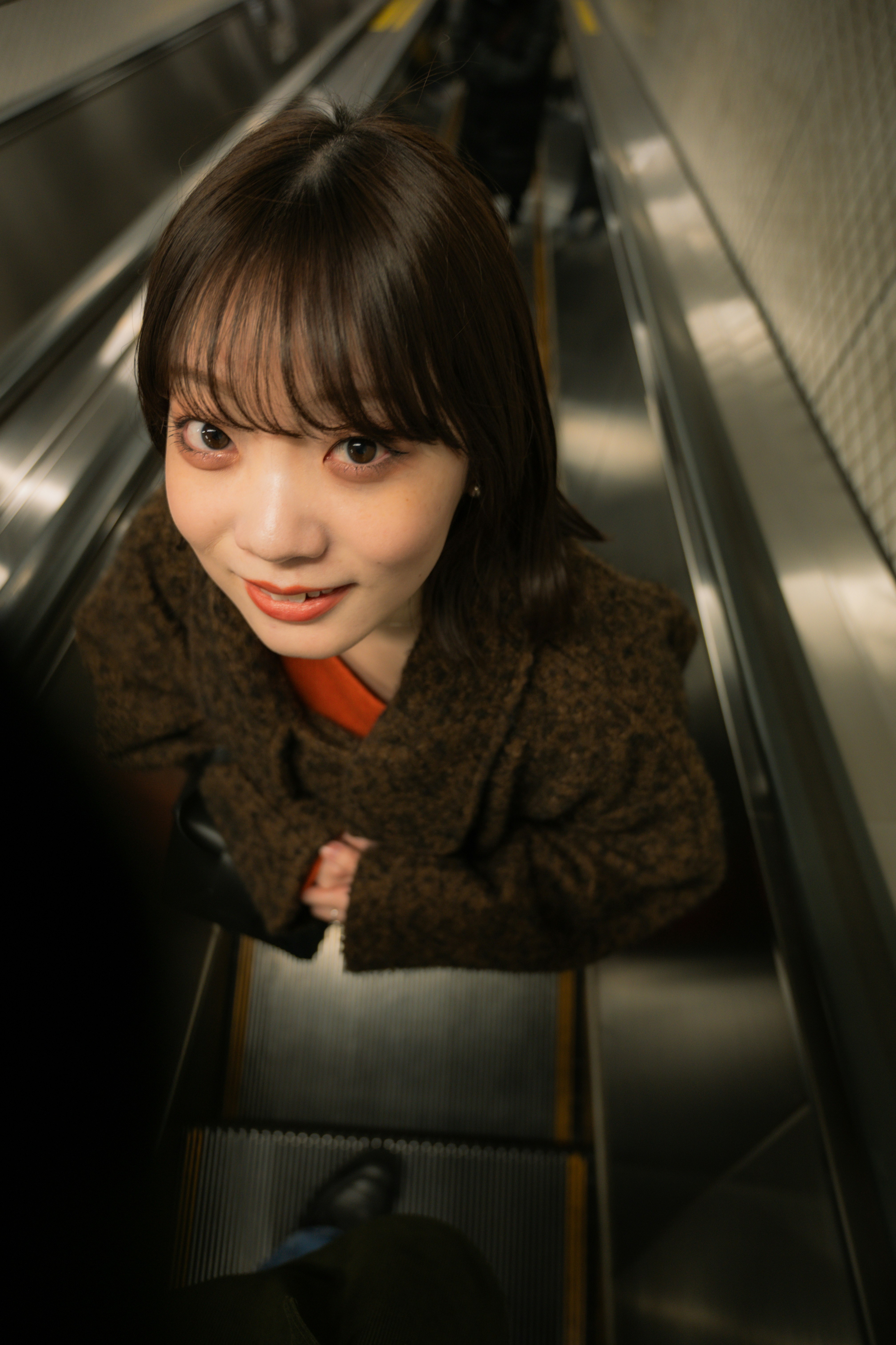 エスカレーターでこちらを見つめる女性