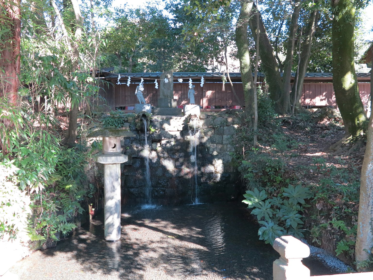 A serene scene featuring a small waterfall and tranquil pond surrounded by greenery