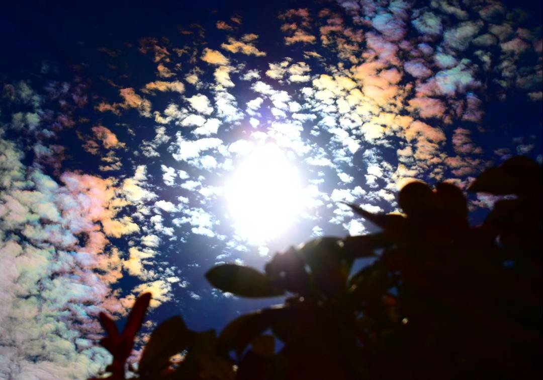 彩雲の輪っかのように広がる虹色の雲と月明かりの空