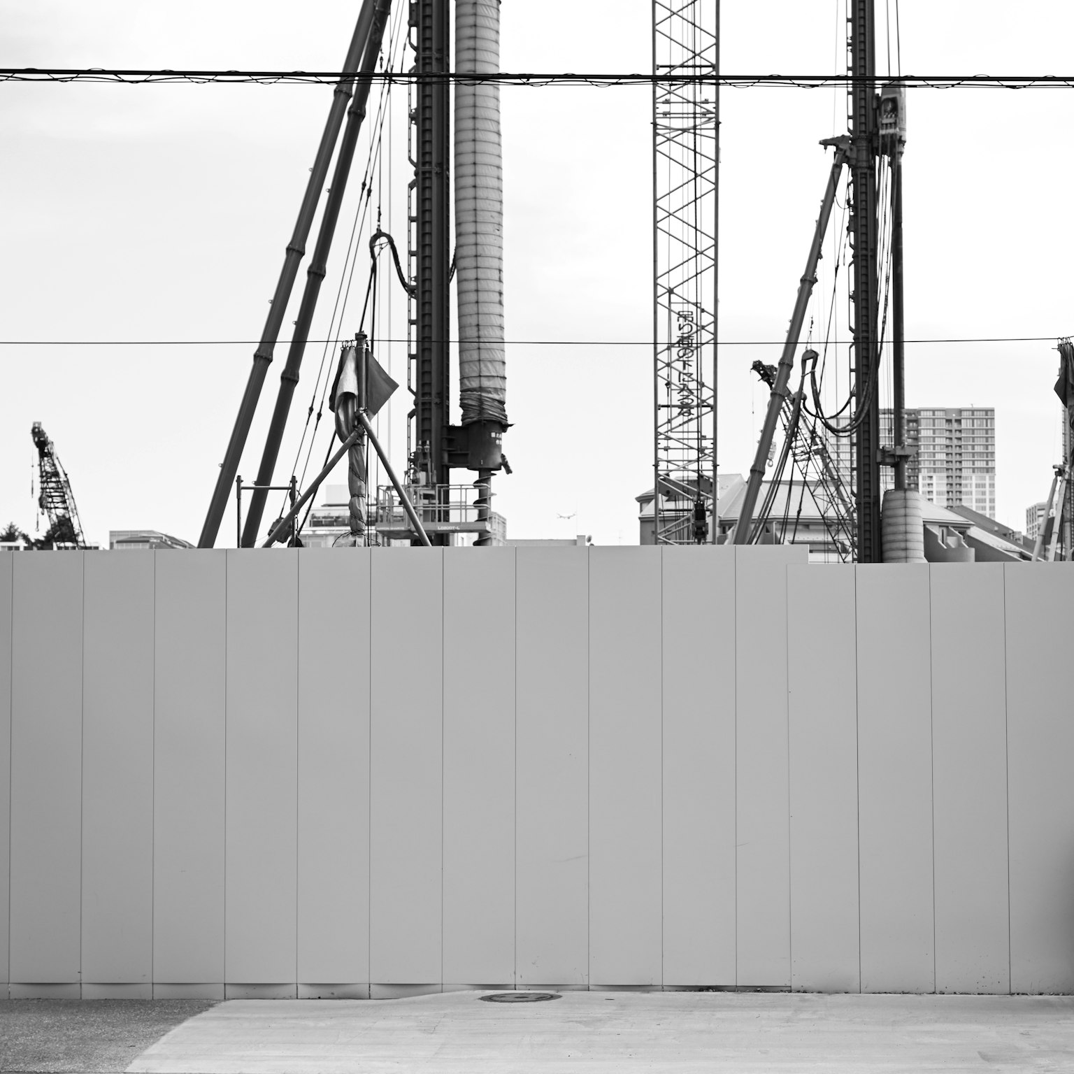 Baukräne und Arbeiter hinter einer weißen Wand