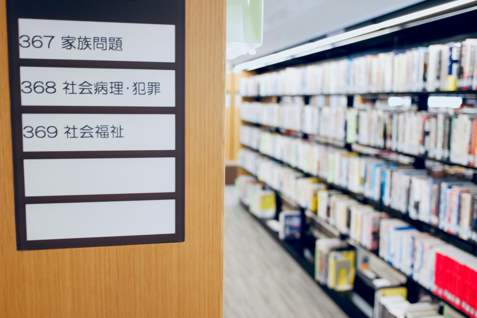 Signboard near a library bookshelf with book spines visible