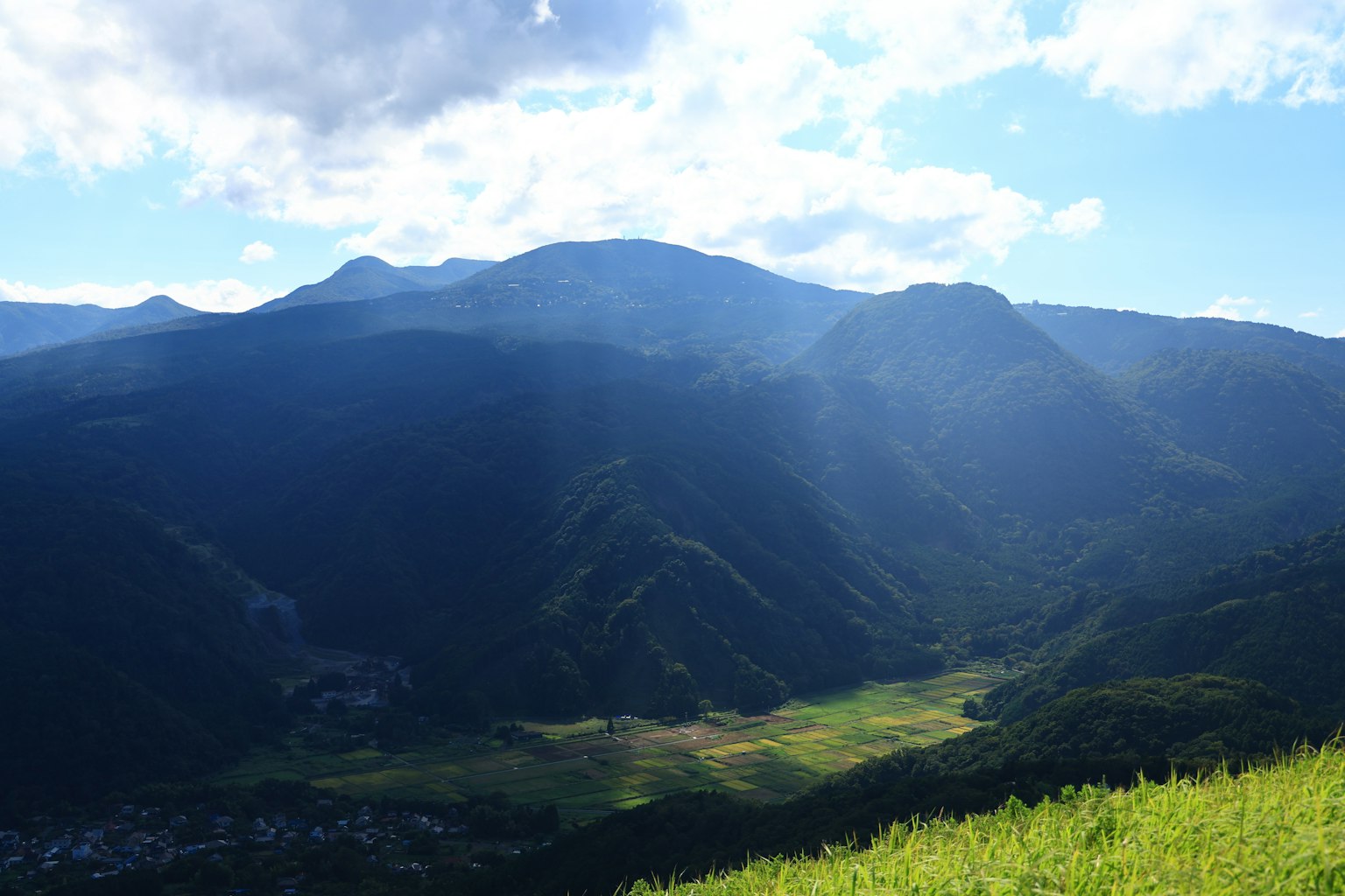 Vista escénica de montañas con cielo azul valle verde abajo