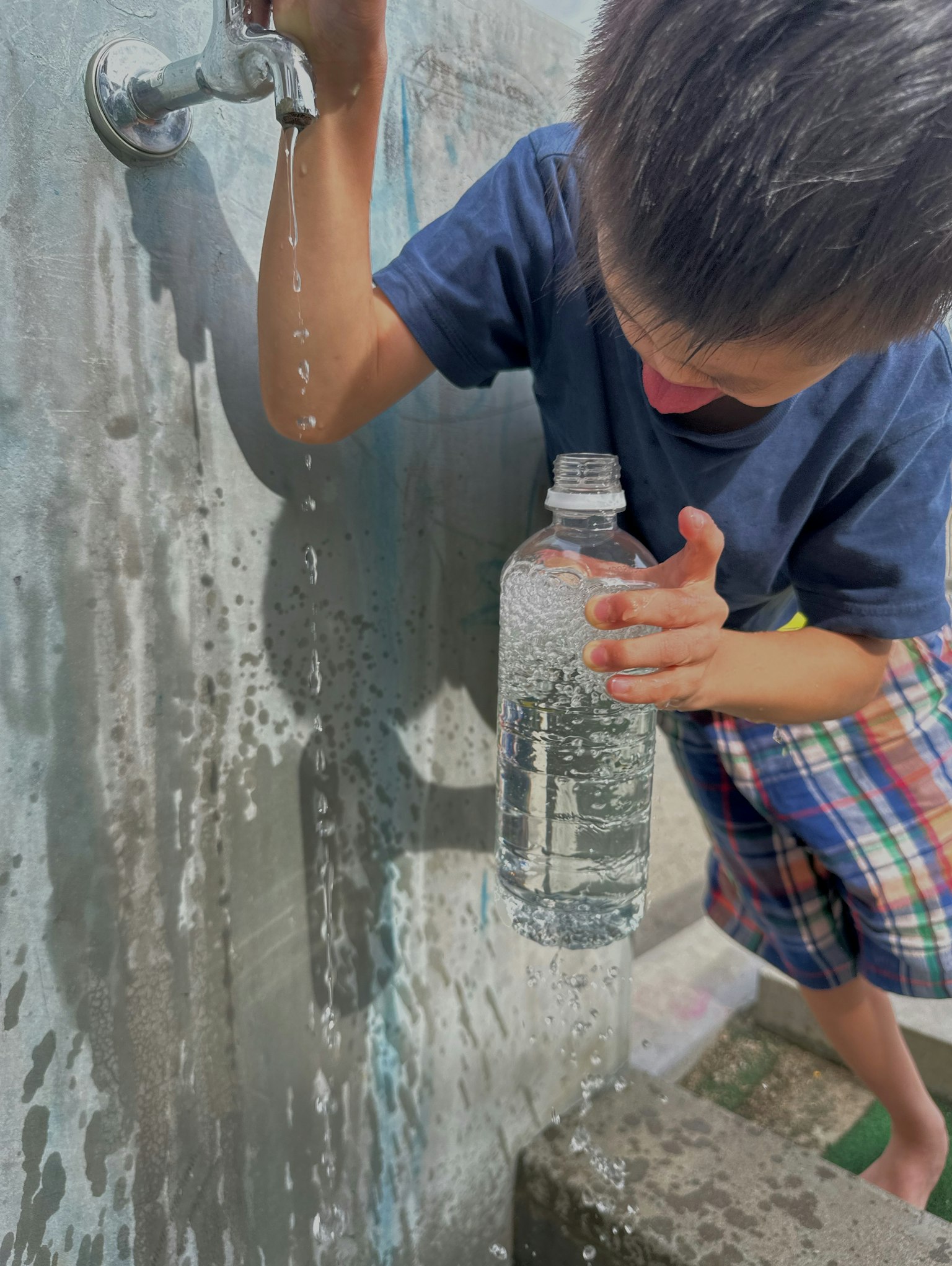Seorang anak mengisi botol air di keran air mengalir dari keran