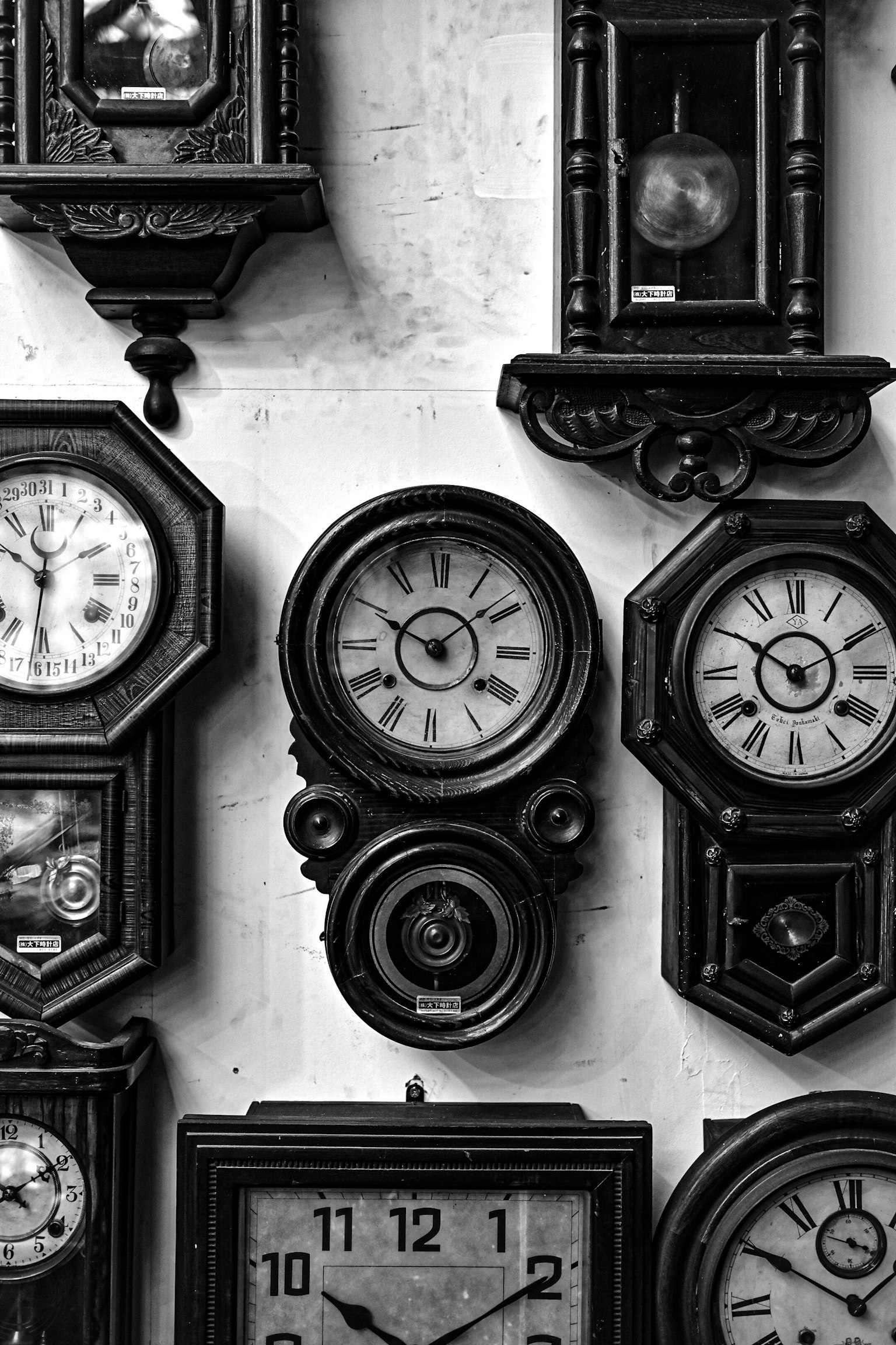 多様なデザインの古い時計が壁に掛けられている