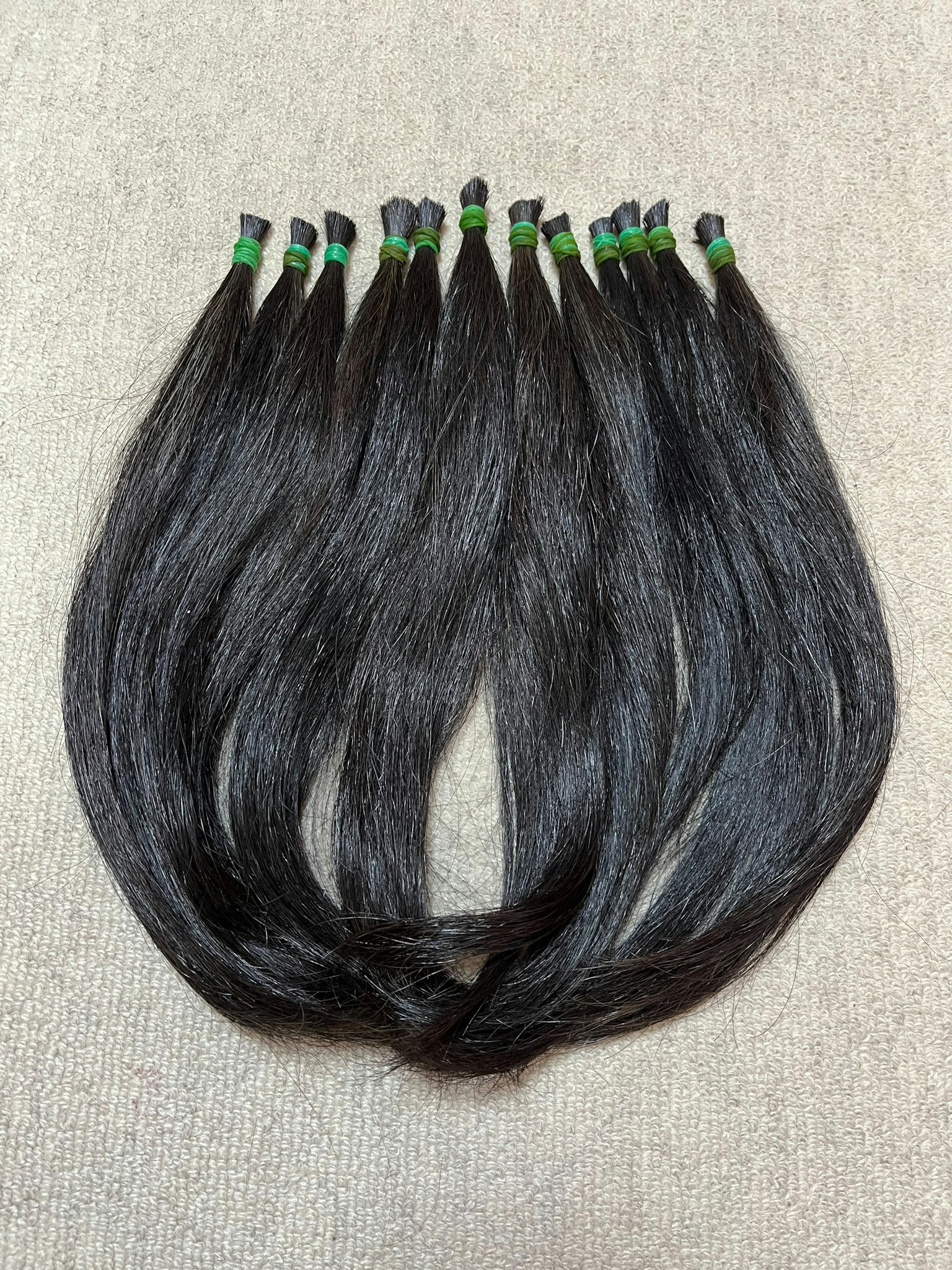 Ikatan rambut hitam yang rapi dengan karet hijau