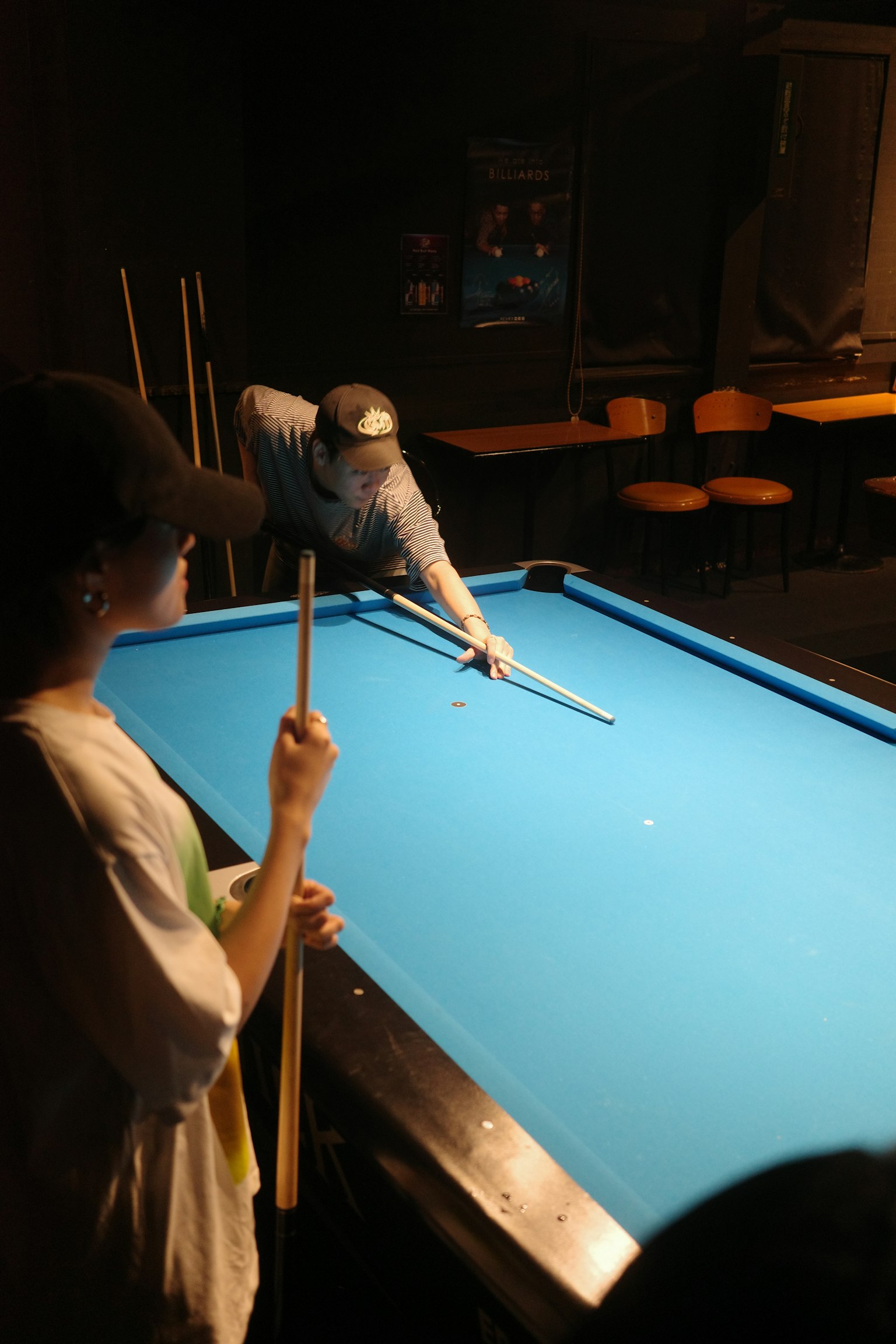 Szene einer Person, die Billard spielt, mit einem Zuschauer Blauer Tisch und dunkler Hintergrund