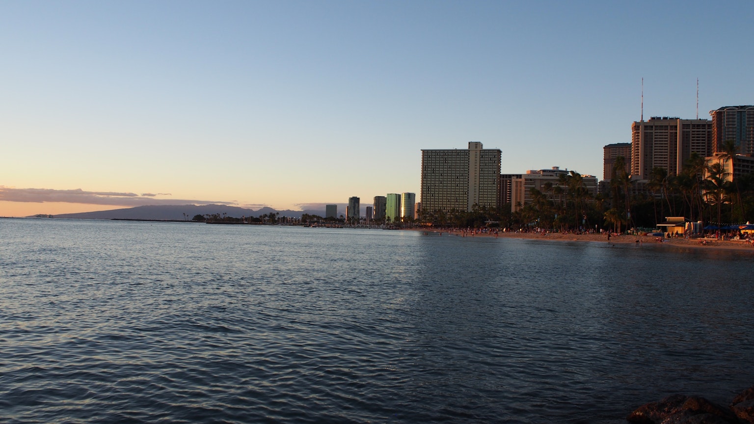 Vista sull'oceano al tramonto con grattacieli lungo la spiaggia di Waikiki