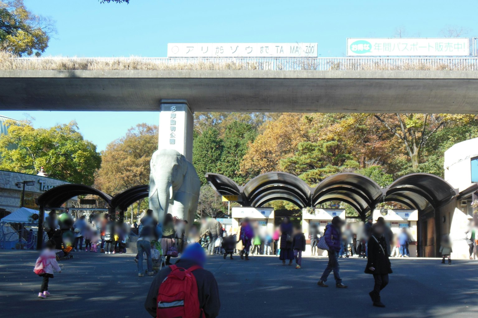 Une entrée de parc animée avec des gens rassemblés Grande sculpture d'éléphant et structures de toit uniques